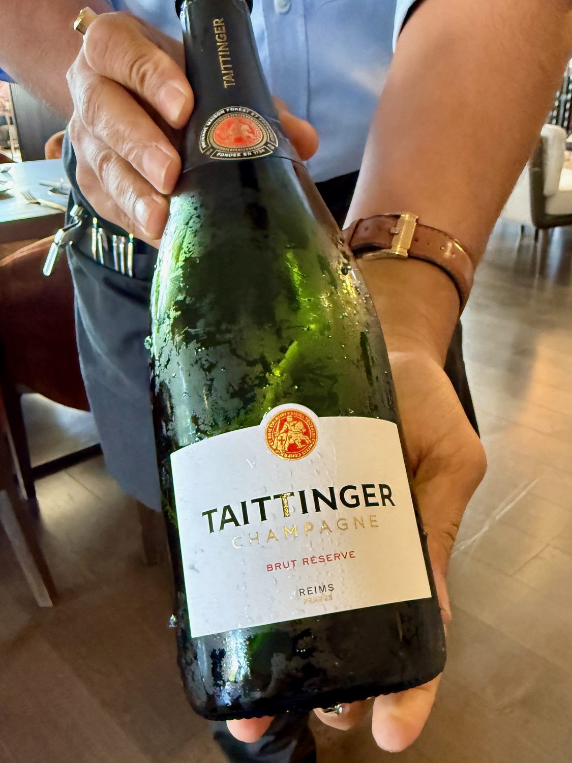 A chilled bottle of Taittinger Brut Reserve Champagne presented at the table
