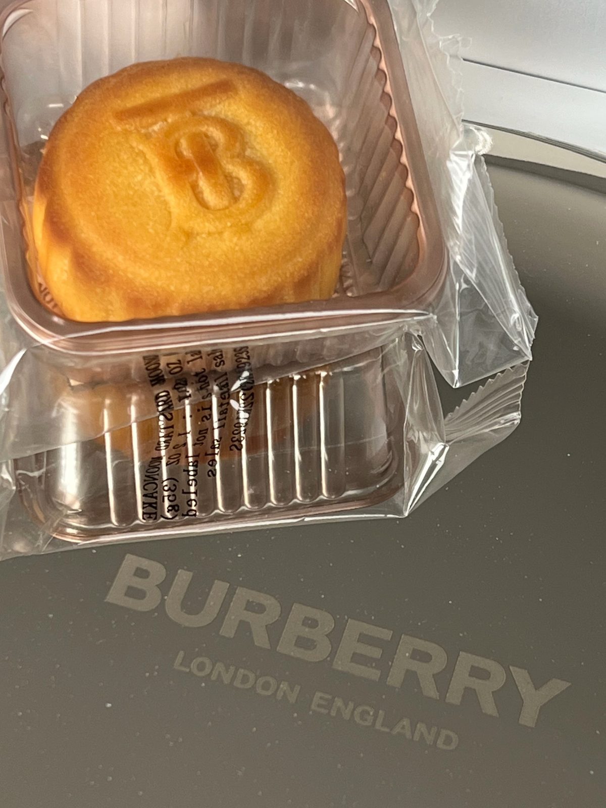 A small wrapped custard mooncake stamped with a TB monogram