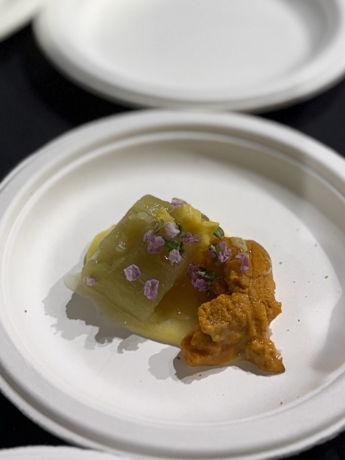 Raw uni lobes beside a block of chilled fried eggplant on corn mousse, scattered with purple shiso blossoms