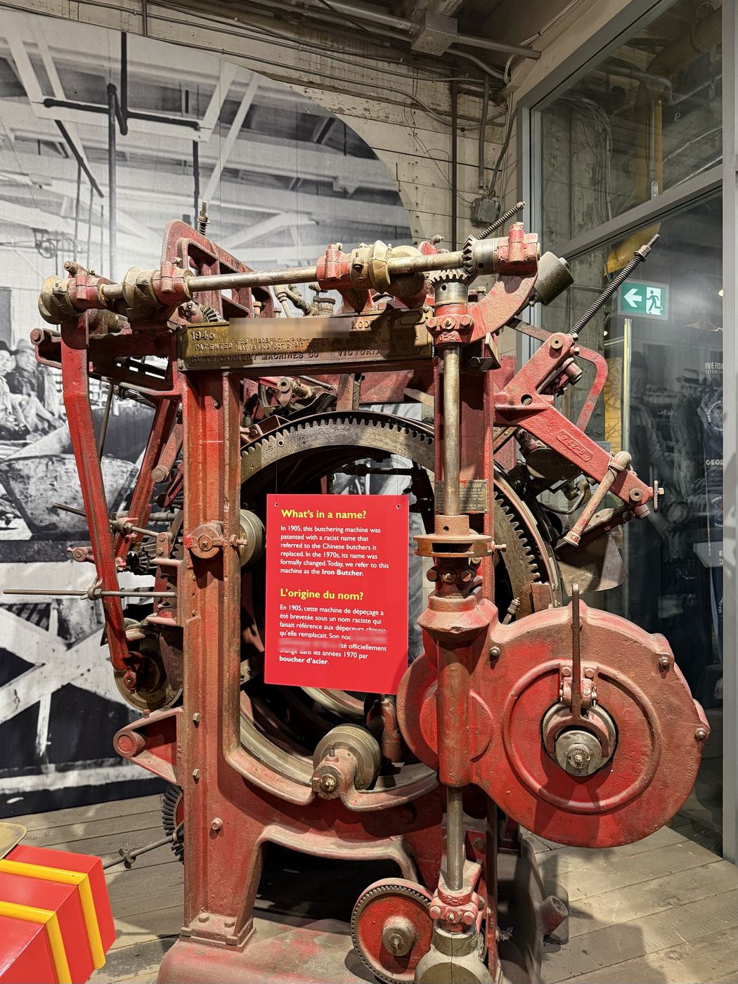 A red cast-iron fish-butchering machine on display at the cannery, beside the museum’s bilingual panel about its renaming