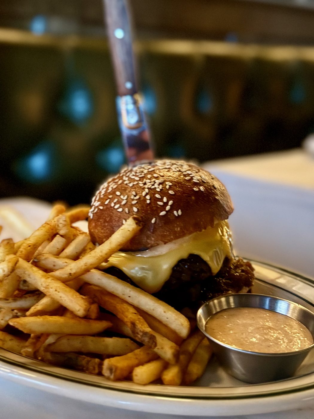 A thick burger with melted cheese and caramelized onions on a duck-fat bun, served with fries