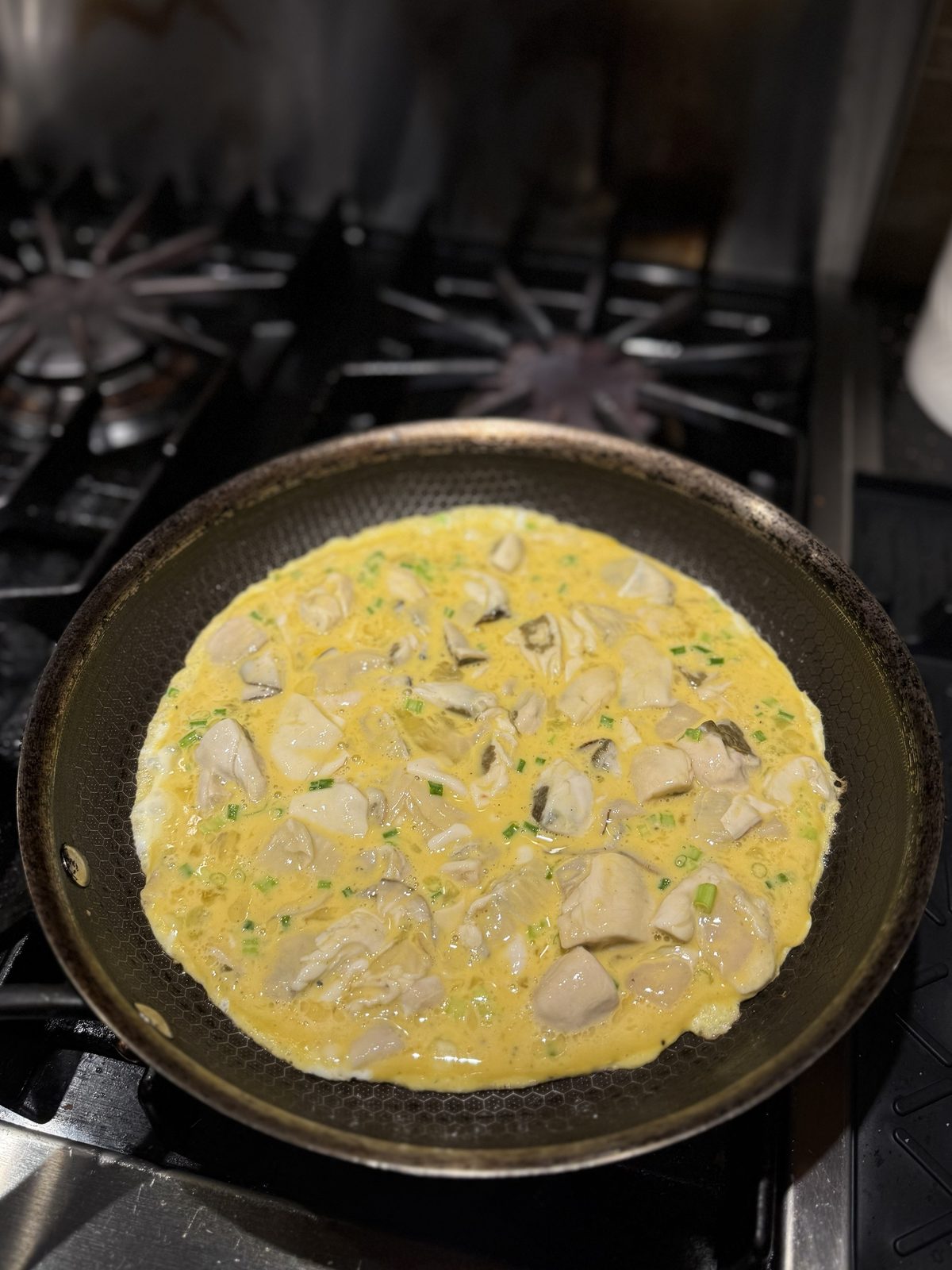 Oyster omelette batter just poured into a non-stick frying pan on a gas stove