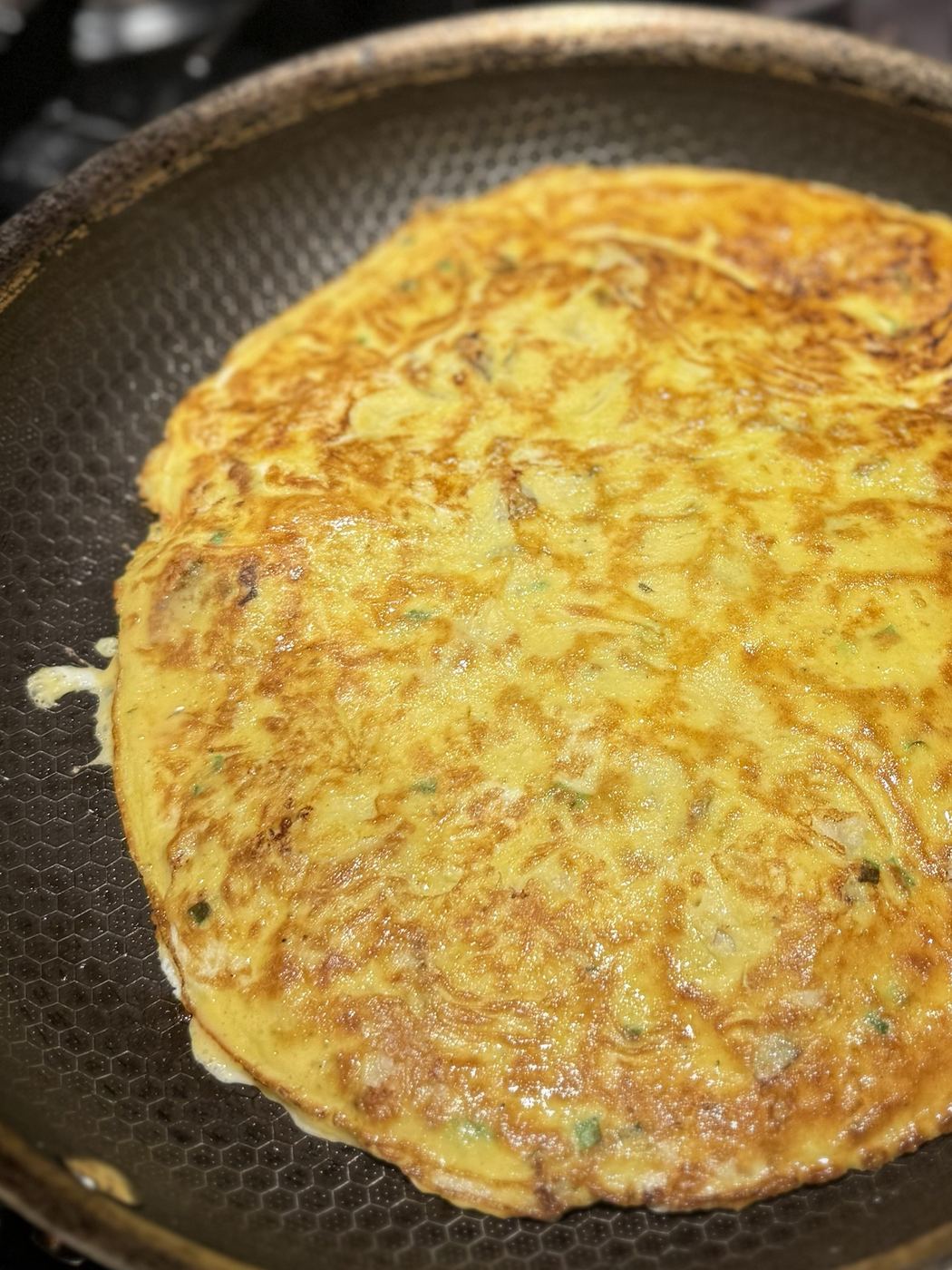 The flipped omelette in the pan, golden brown on the cooked side