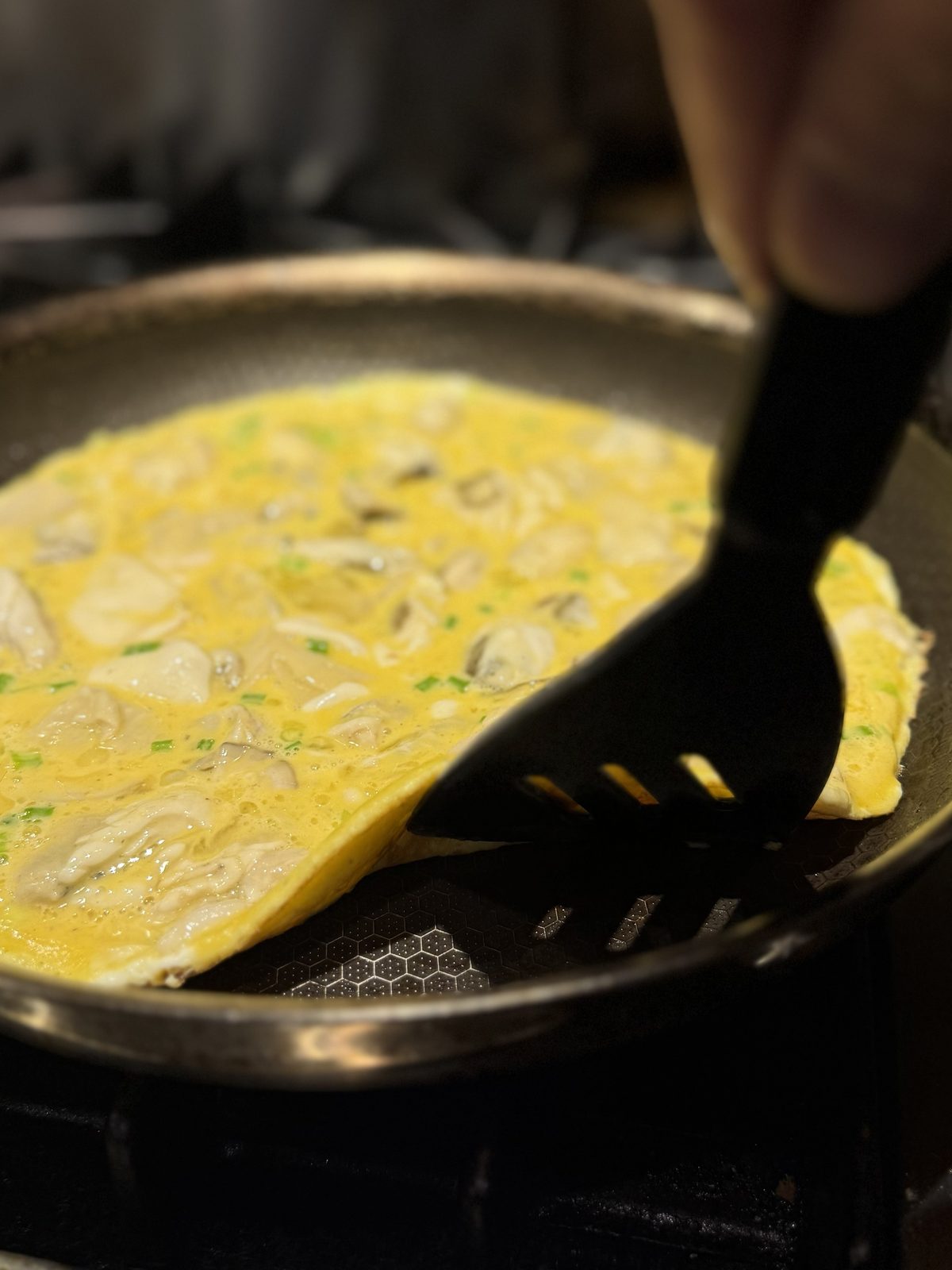 A spatula lifting the edge of the omelette to check the underside