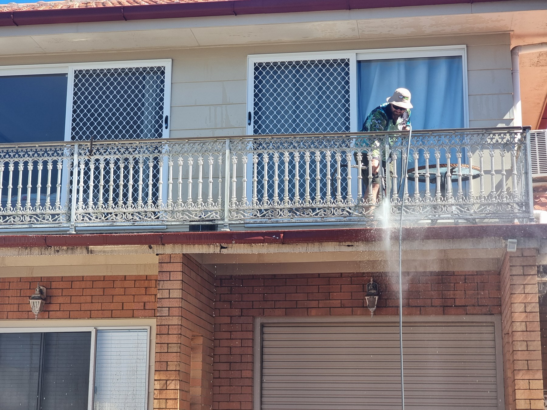 TopWash crew soft washing the balcony and iron railings of a two-storey Toowoomba home