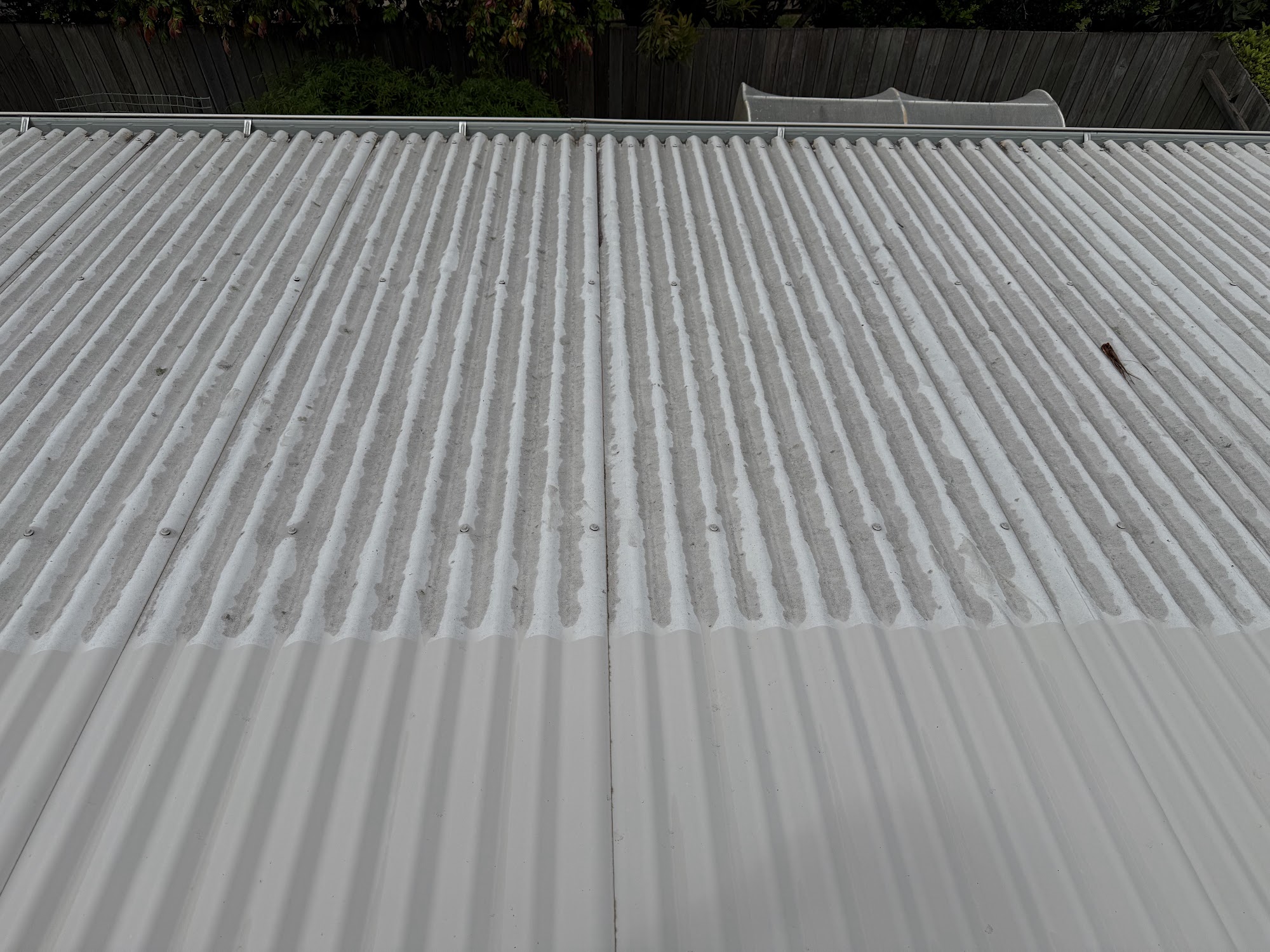 Metal roof in Toowoomba part-way through a soft wash, the cleaned half clearly lighter than the grimy half