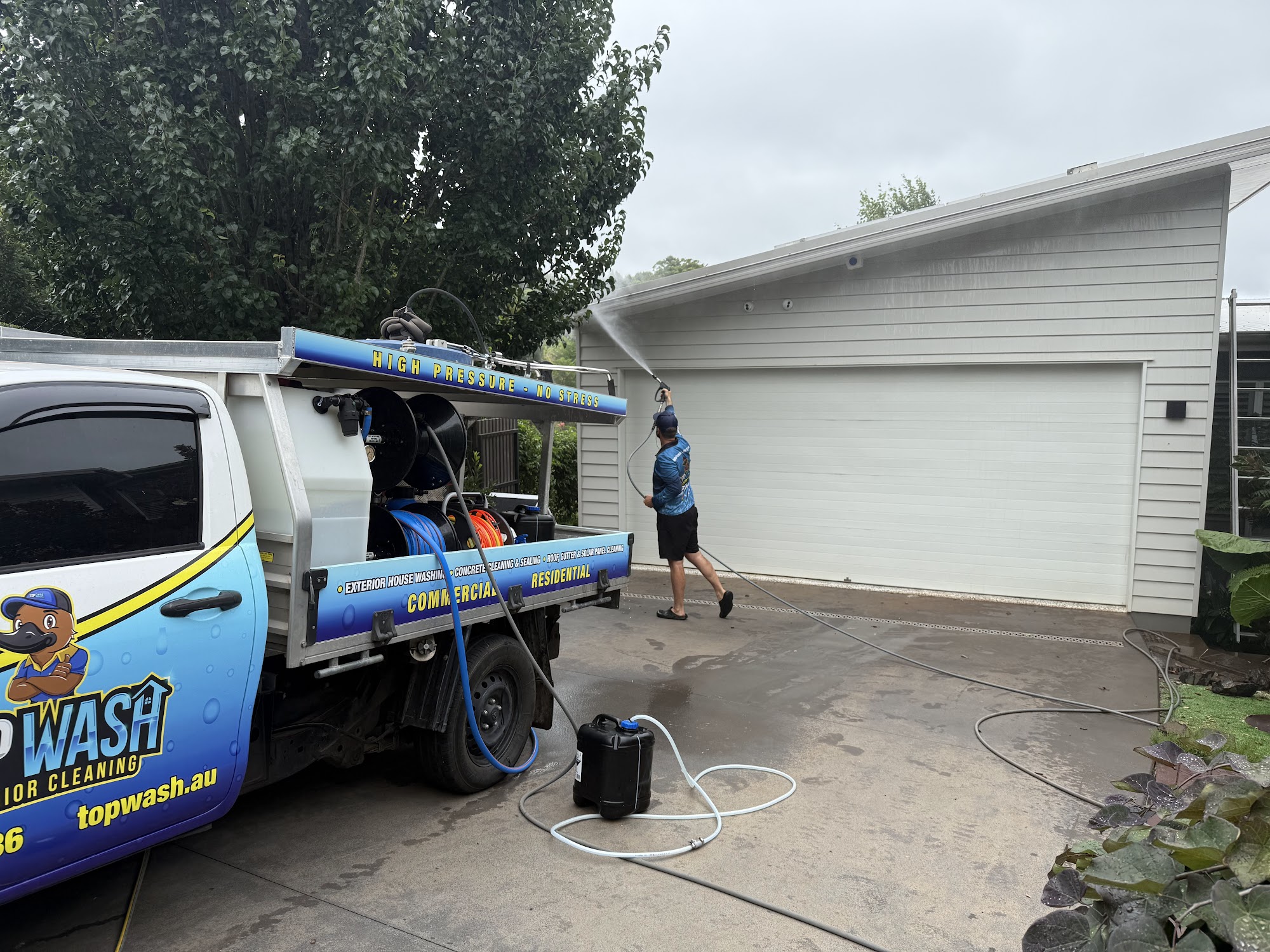 TopWash ute and pressure cleaning rig set up on a driveway while the garage door is washed