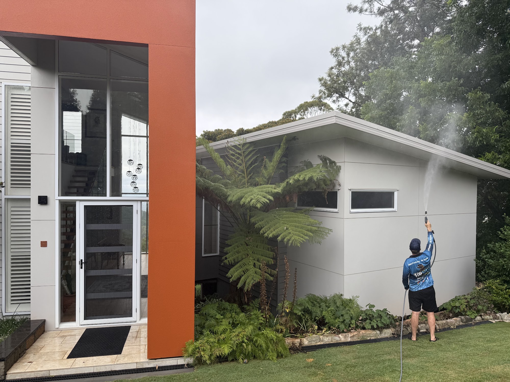 Soft wash solution going onto the rendered wall and eaves of a modern home