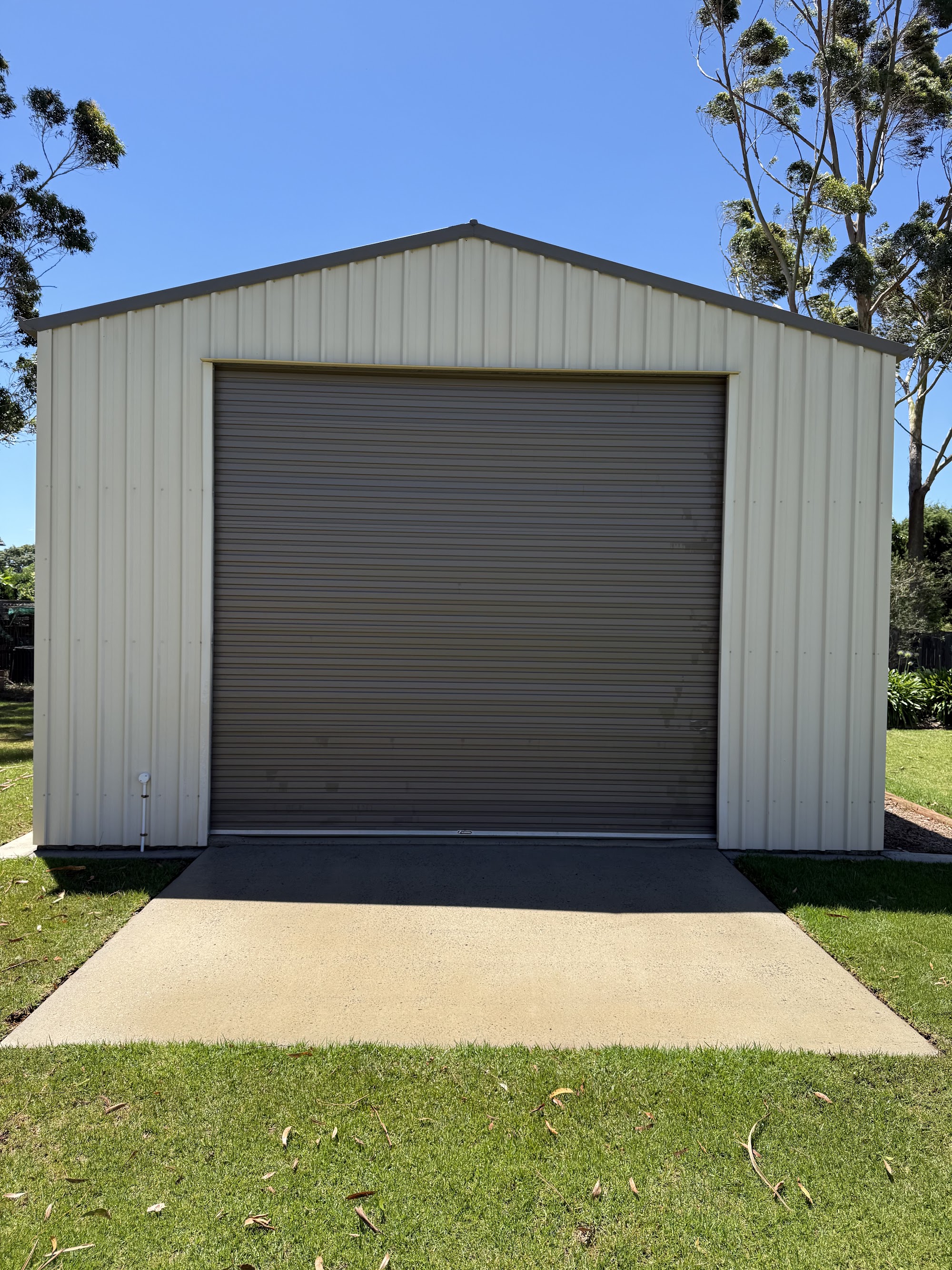 Cream Colorbond shed with a roller door, cleaned by TopWash in Highfields