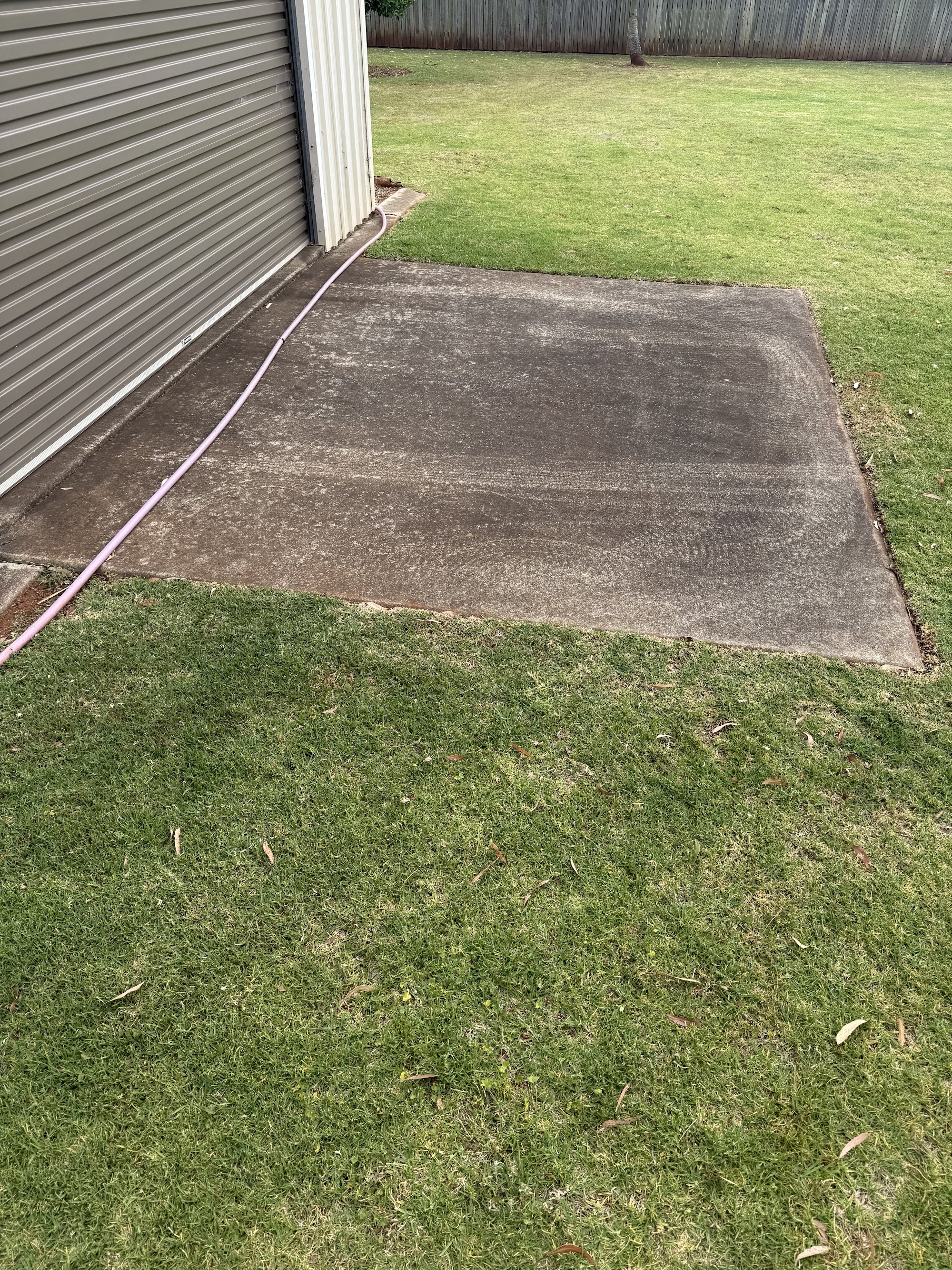 Concrete shed apron stained grey with dirt before pressure cleaning