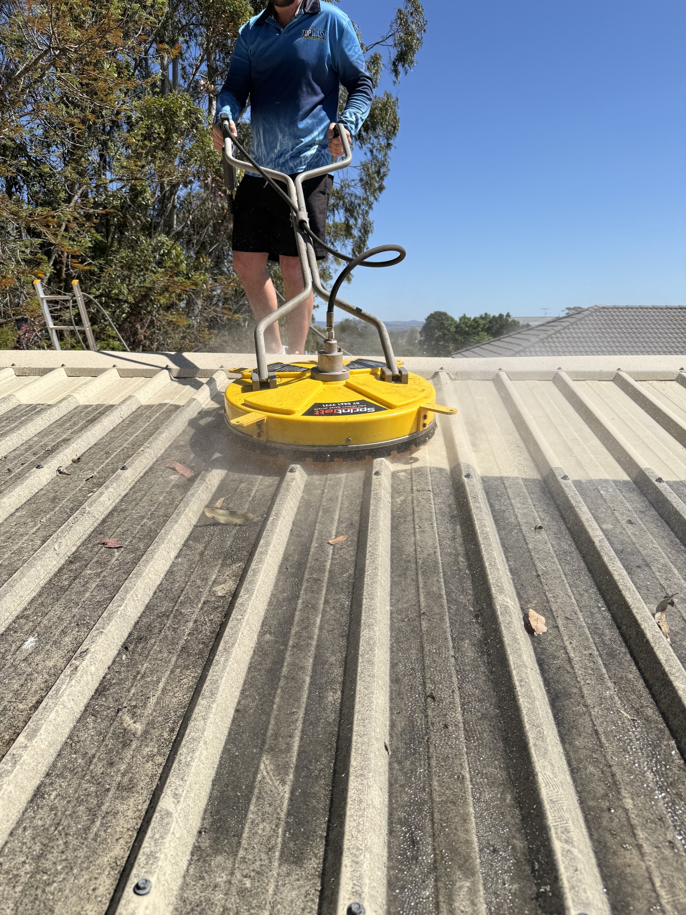 TopWash crew running a surface cleaner across a metal roof in Toowoomba