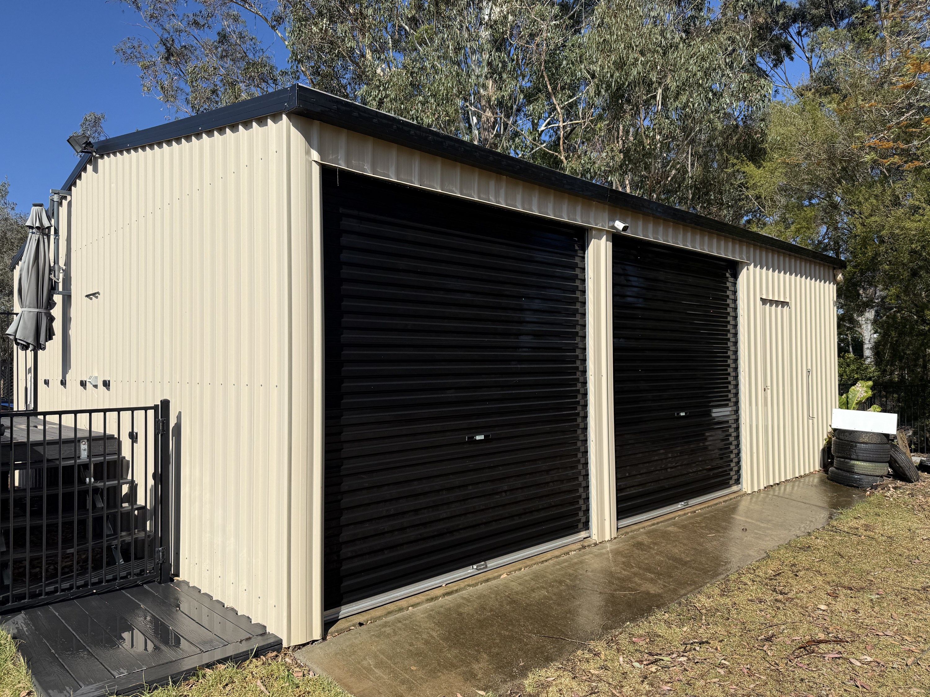 Cream Colorbond shed with roller doors, cleaned by TopWash in Highfields
