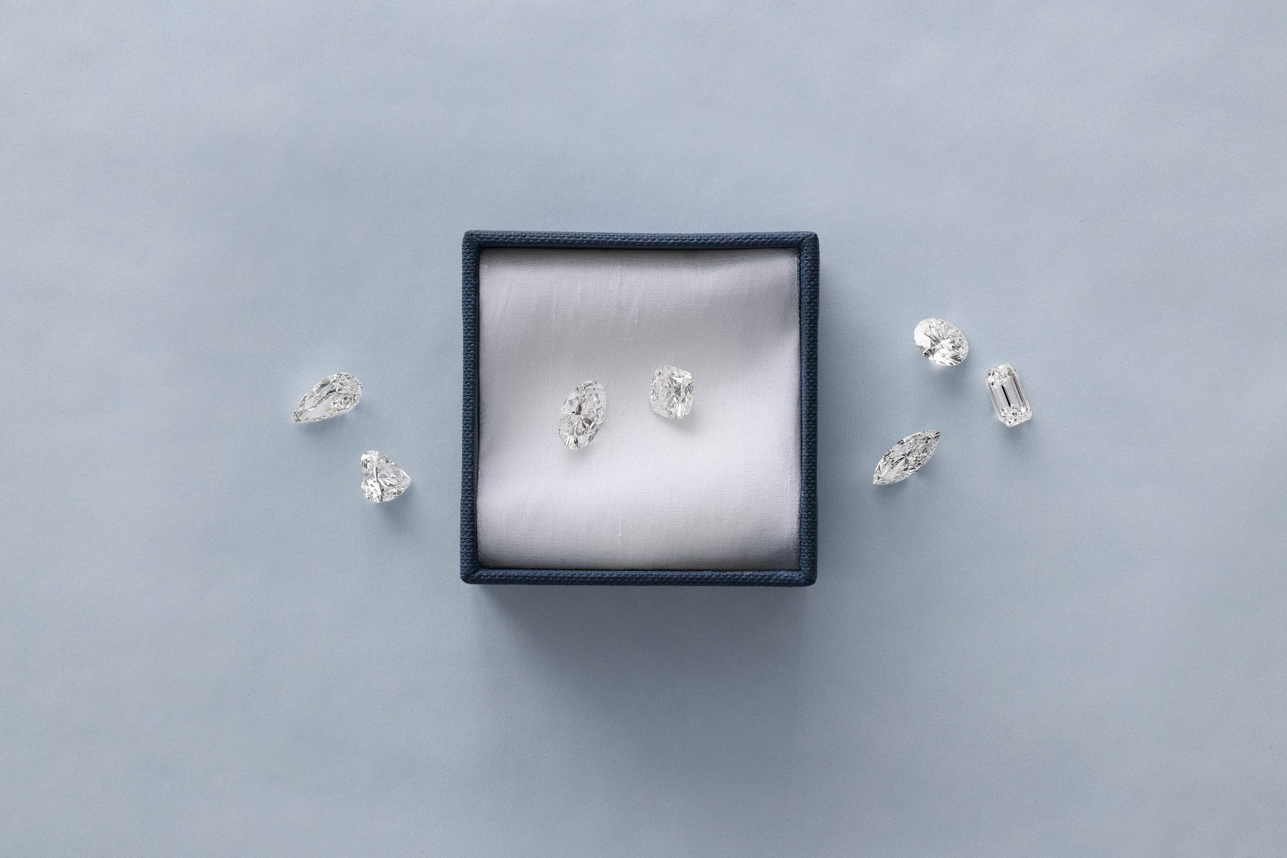 Blue Nile loose diamonds in assorted cuts arranged around a navy presentation box