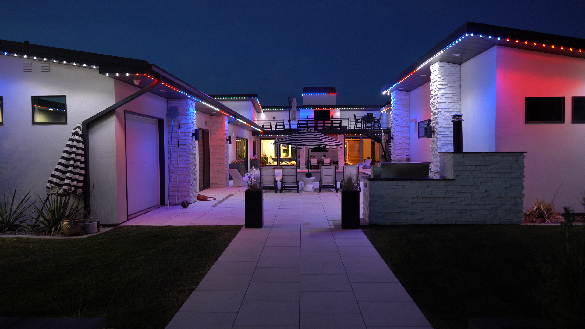 Modern home illuminated with red, white, and blue permanent roofline lighting