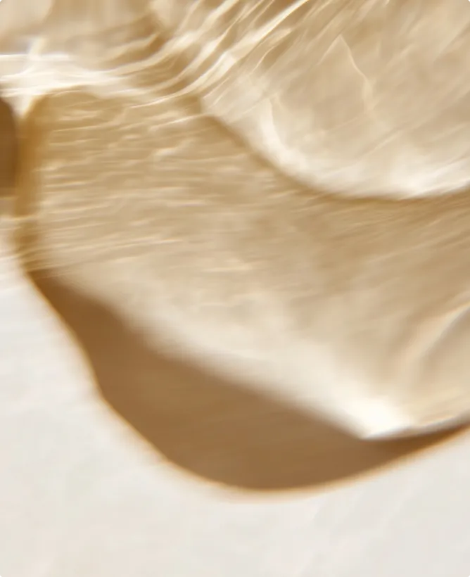 Abstract close-up image of light patterns and shadows on a smooth, pale surface, creating a fluid and soft texture effect.