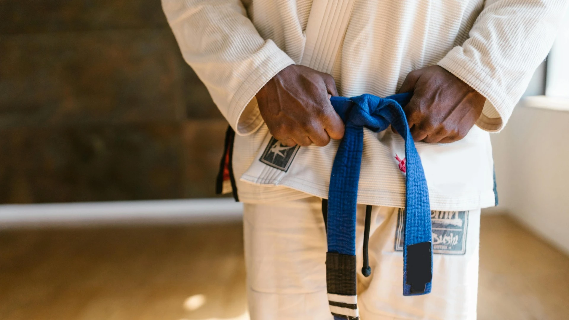 Close-up of a martial artist holding the blue belt on a white uniform
