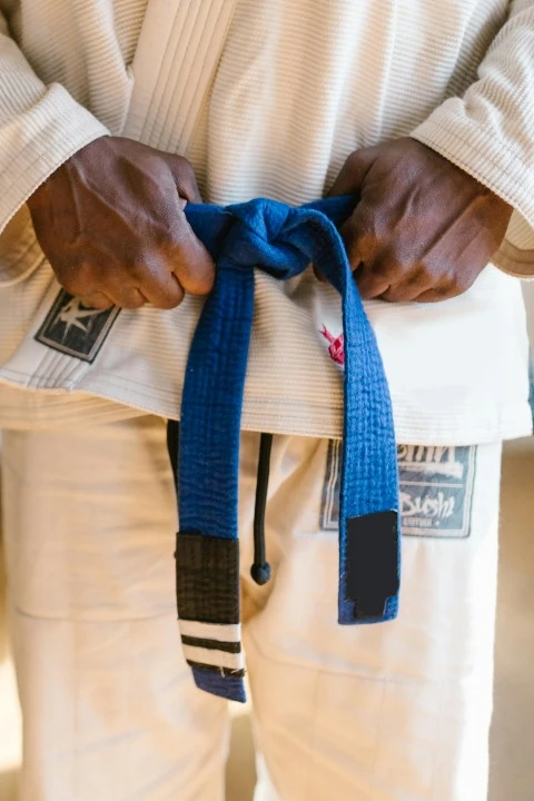 Close-up of a martial artist holding the blue belt on a white uniform
