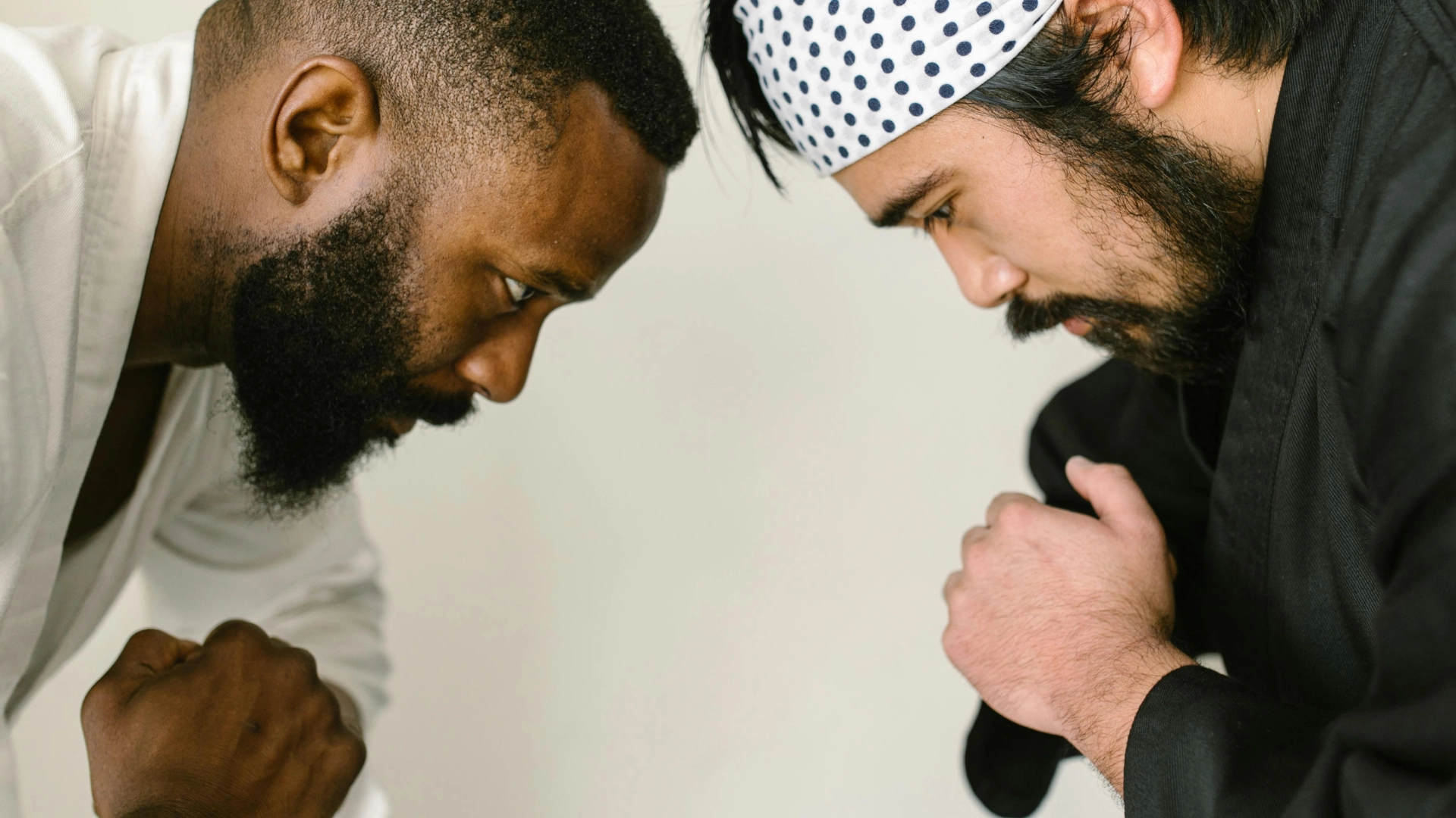 Two martial arts instructors in traditional uniforms facing off in a ready stance