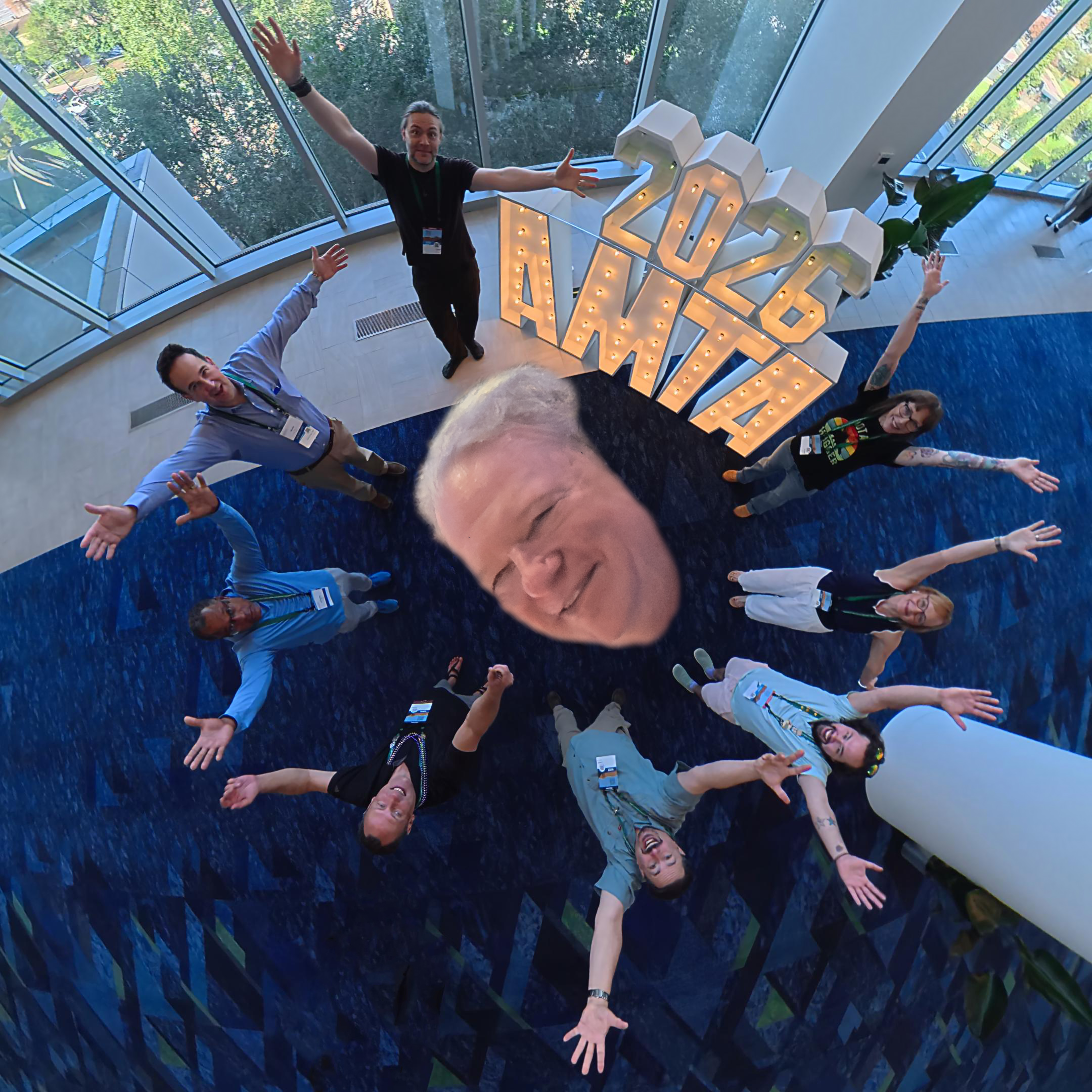A playful 360-degree group photograph around the illuminated 2026 AMTA letters.