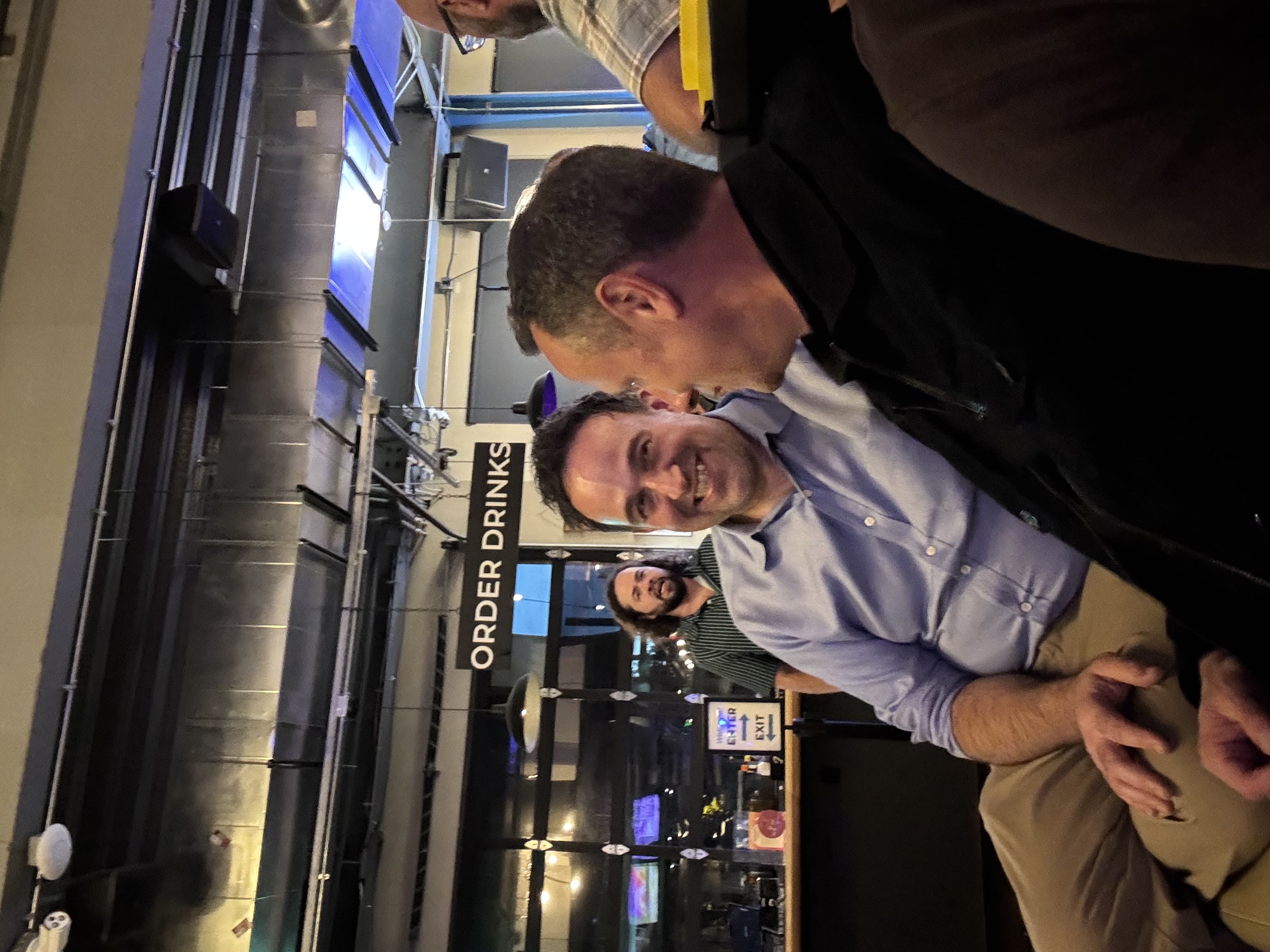 Two attendees seated beside one another in conversation, one smiling toward the camera.