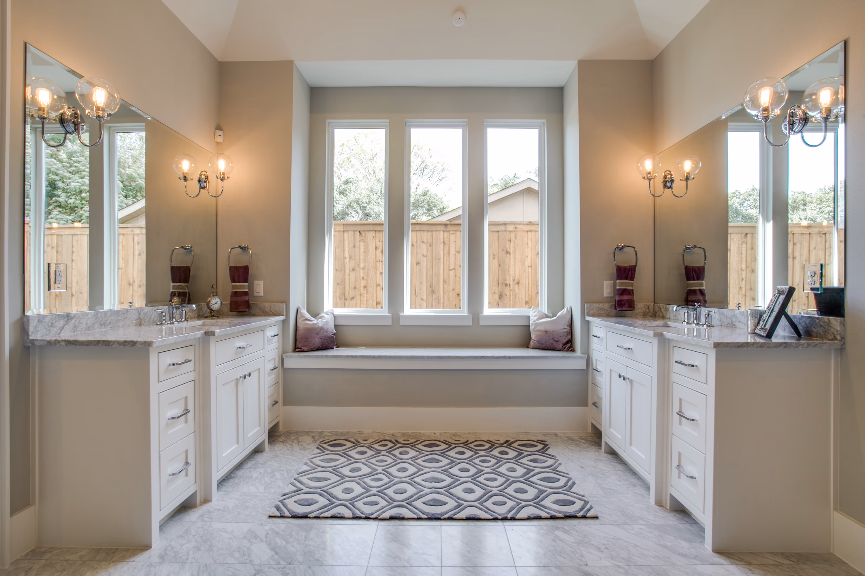 Bathroom vanity and freestanding bathtub beneath tall windows in a completed Cambridge home