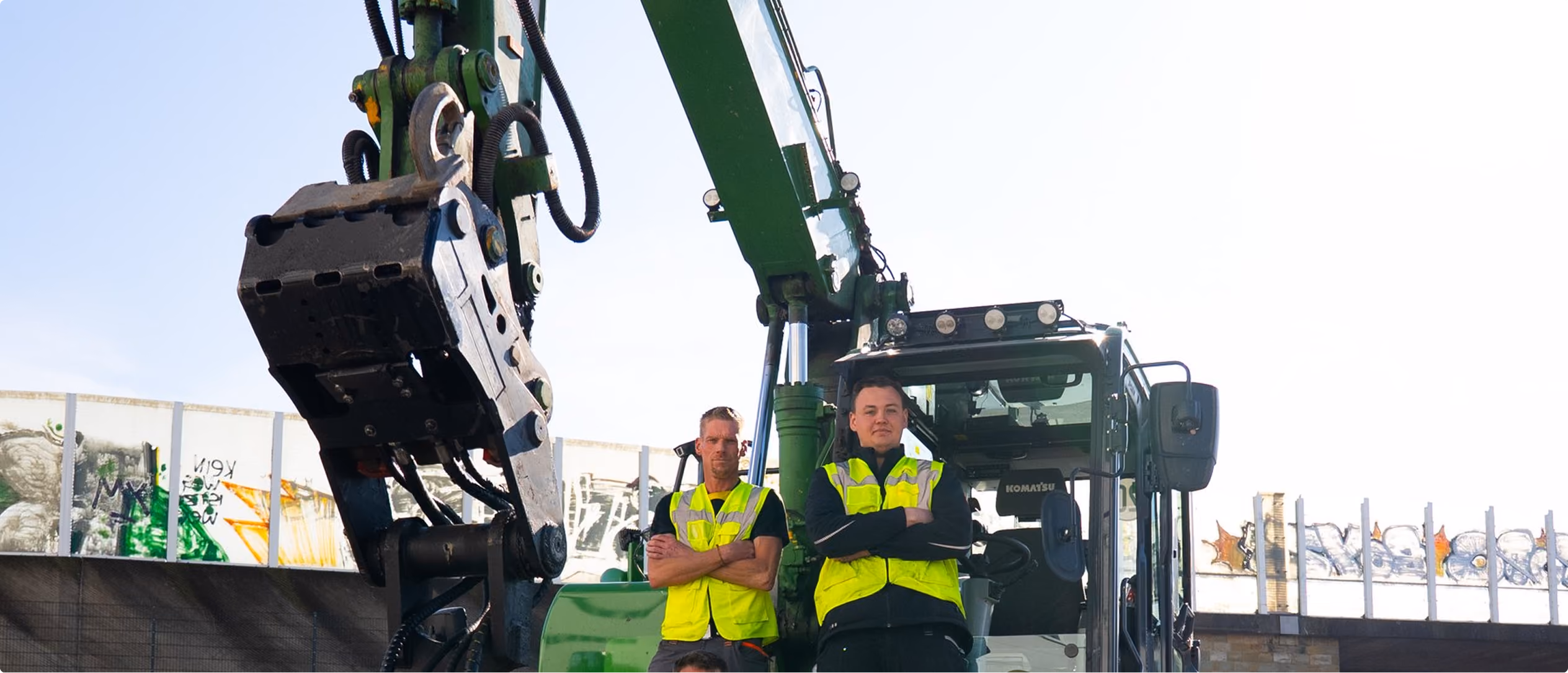 Mitarbeiter vor einem Bagger auf der Baustelle
