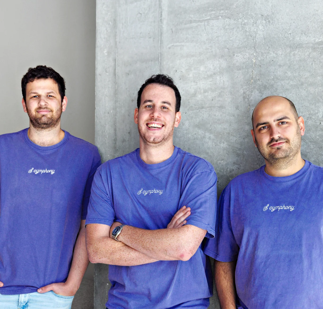 Cymphony's three founders in purple Cymphony t-shirts against a concrete wall — from left to right, Edi Gotlieb, Shy Dekel and Idan Berkovits.