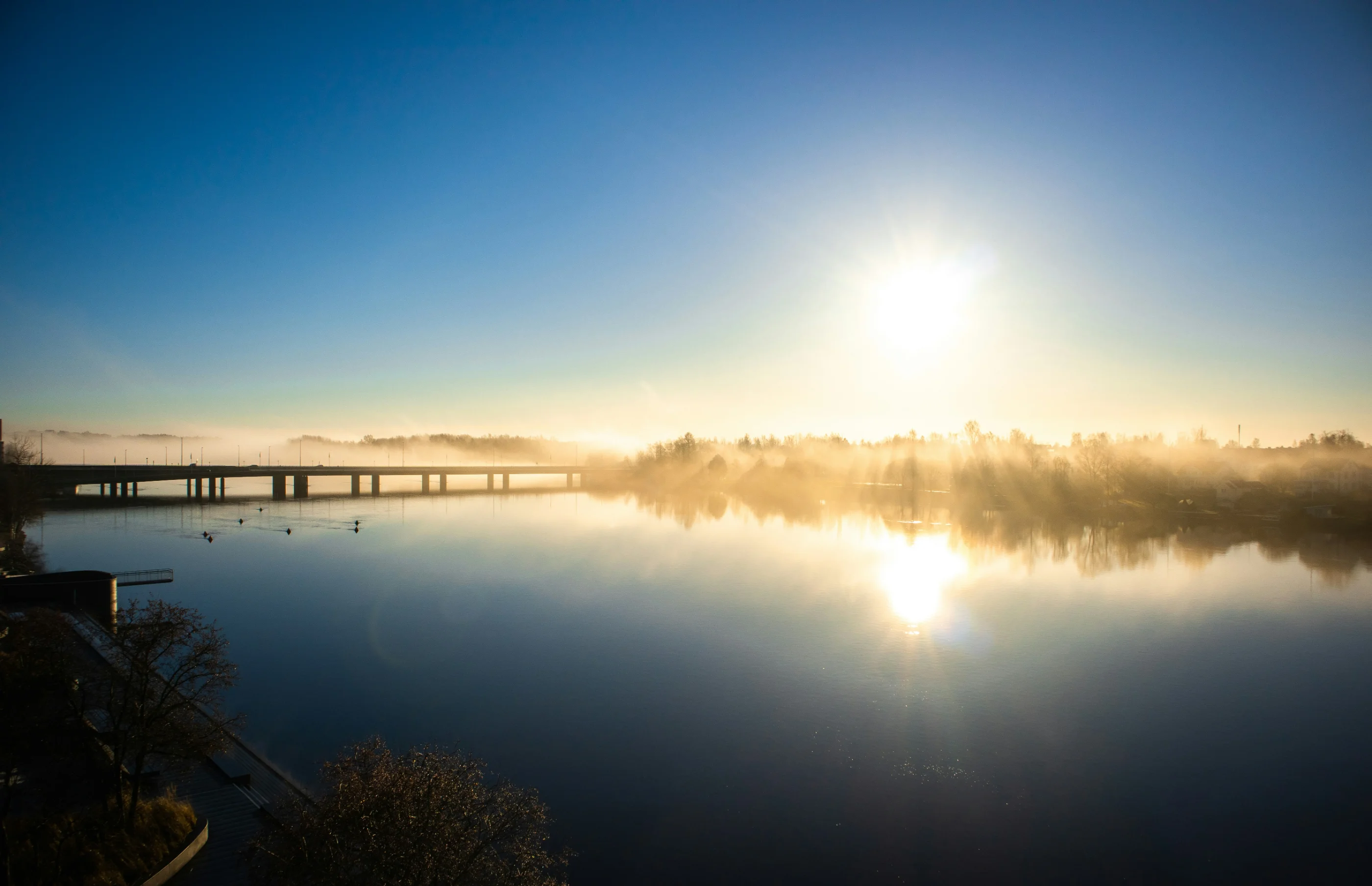 Mist rising off a river at sunrise near Umeå in northern Sweden, with a low bridge crossing the water