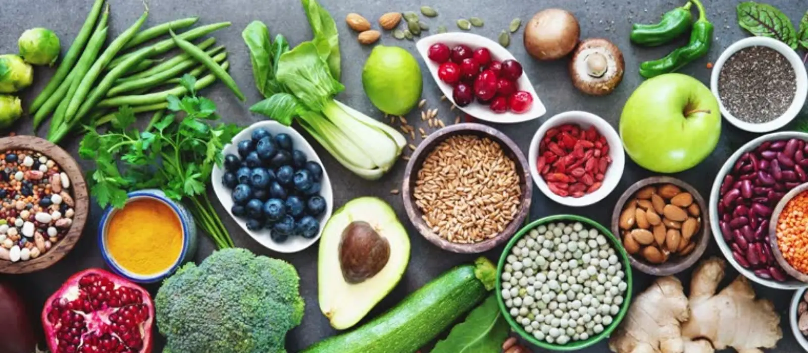Aliments frais disposés à plat : bananes, avocat, saumon, œufs, légumineuses et oléagineux