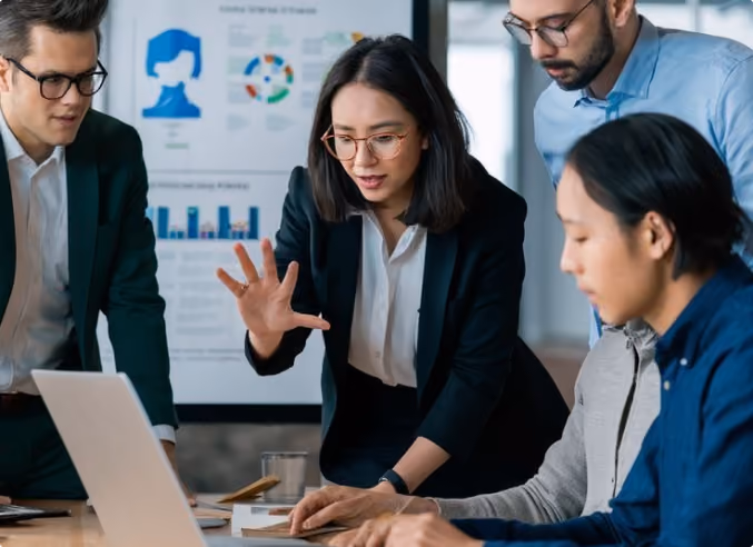 Team of four professionals reviewing data on a laptop in a meeting room