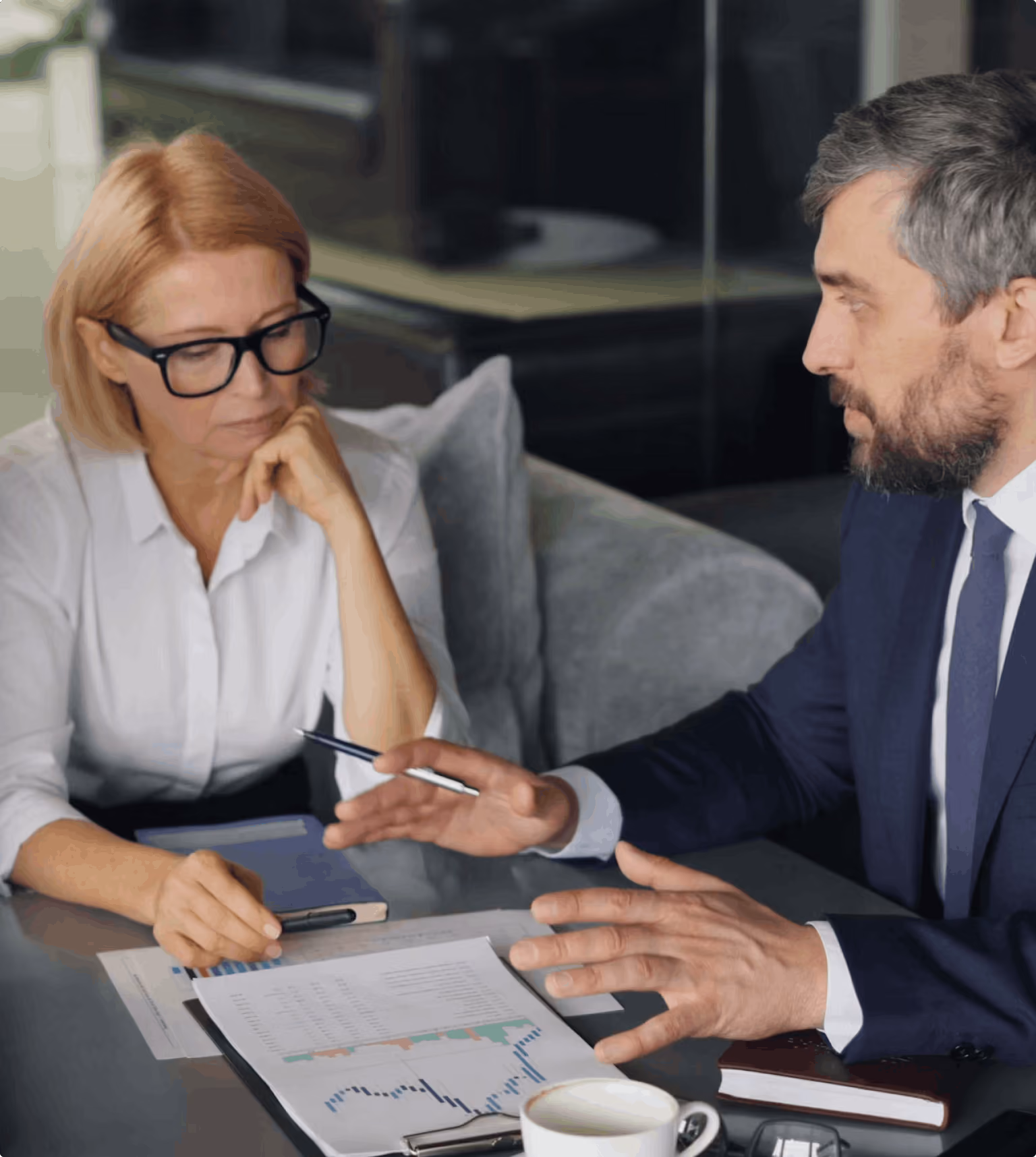 Two senior professionals reviewing hiring data and charts in a meeting