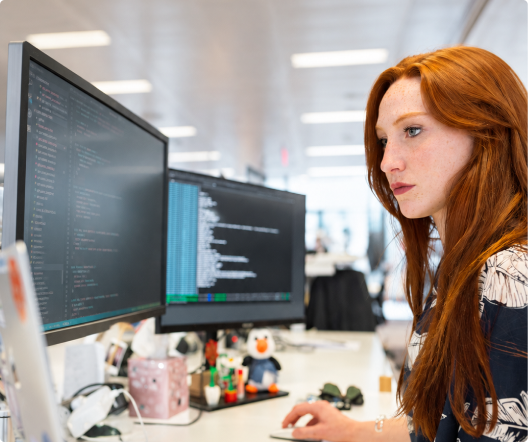 Engineer working at a dual monitor setup in a tech workspace