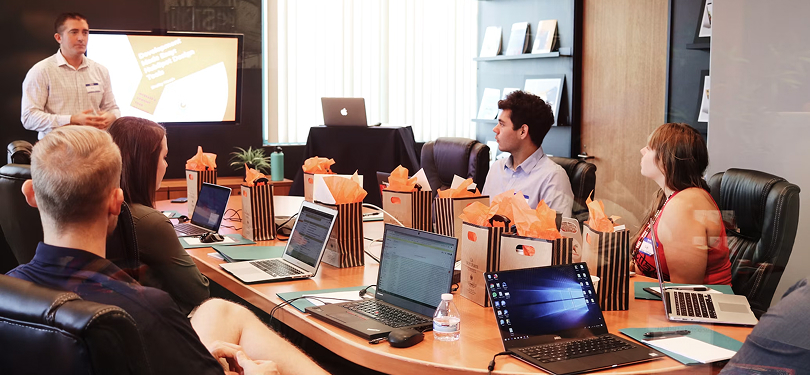 Business team attending a boardroom presentation with laptops and a screen display