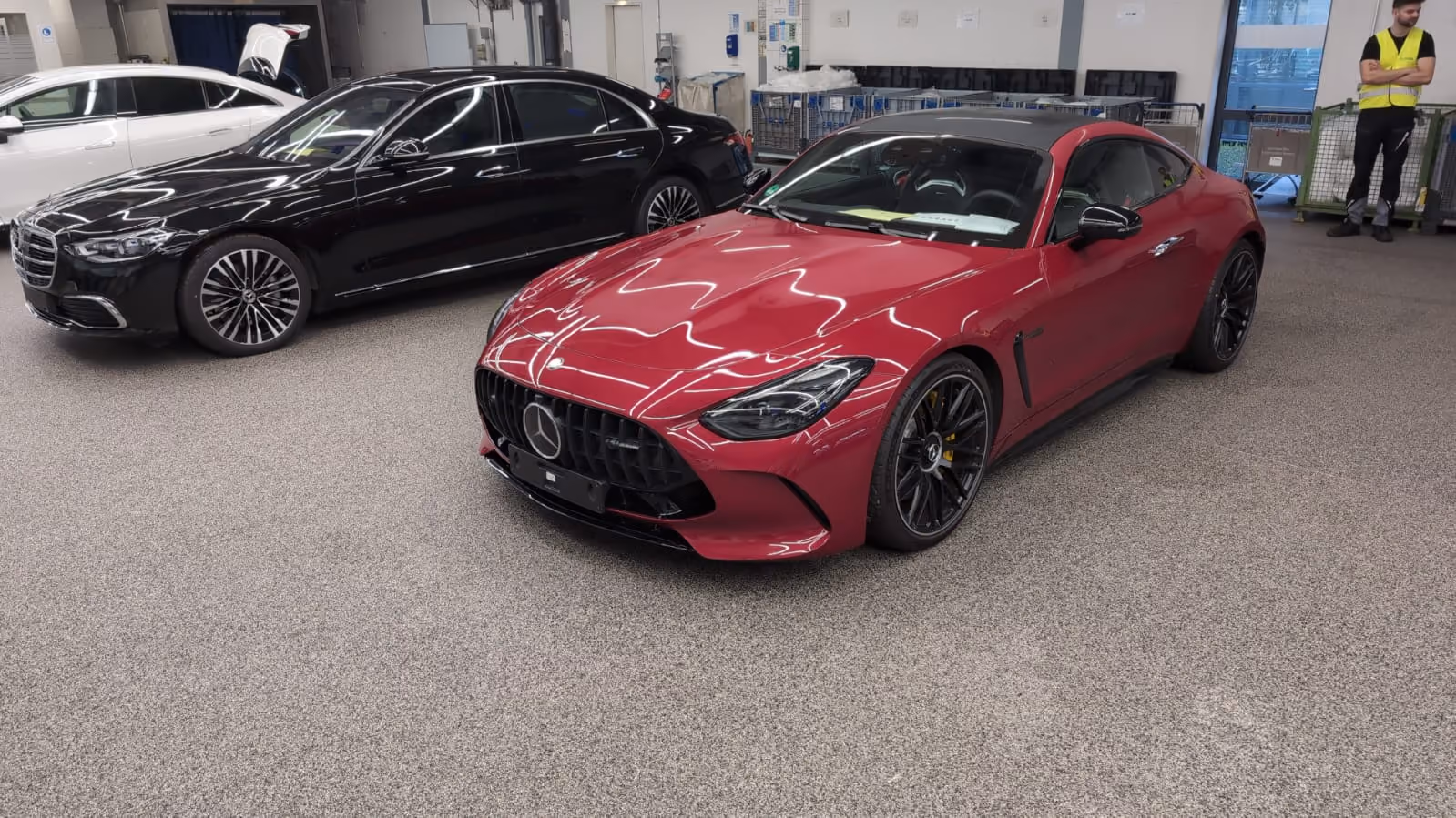 Roter Mercedes-AMG Sportwagen neben schwarzem Mercedes-Benz in einer Werkstatt mit grauem Boden.