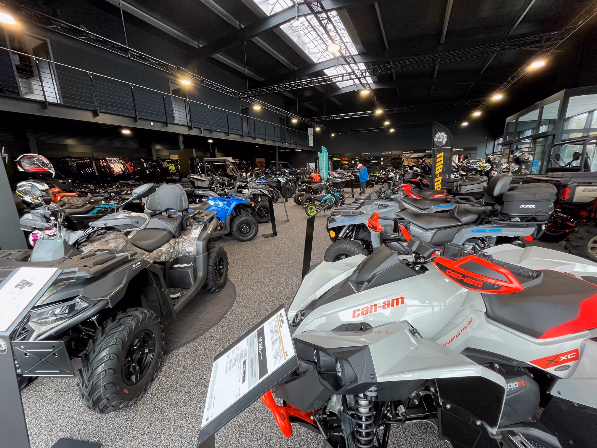Innenansicht eines Ausstellungsraums mit Can-Am Geländefahrzeugen und Motorrädern auf dem Boden.