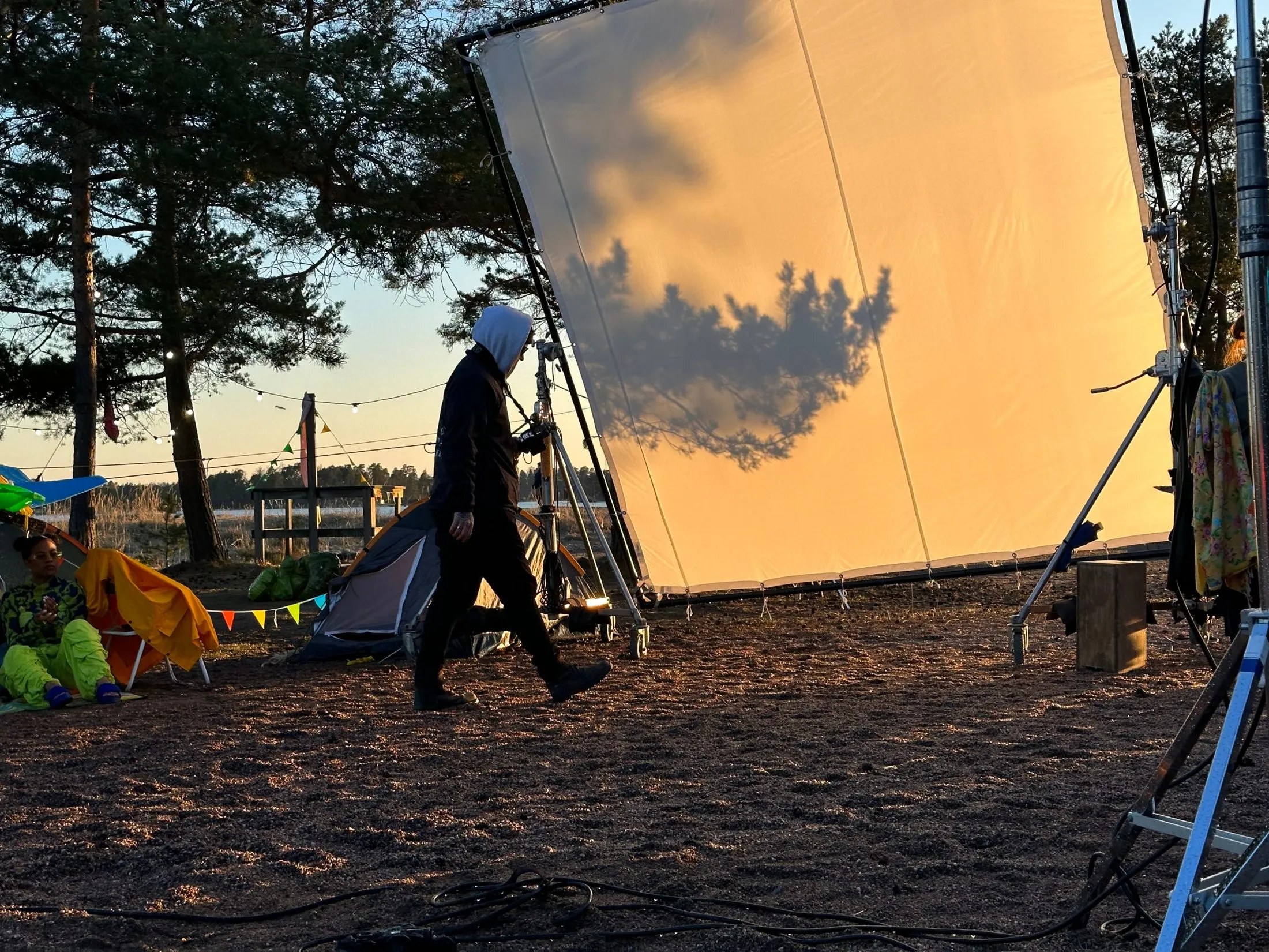 A large diffusion screen and crew member on a sandy beach set at sunset.
