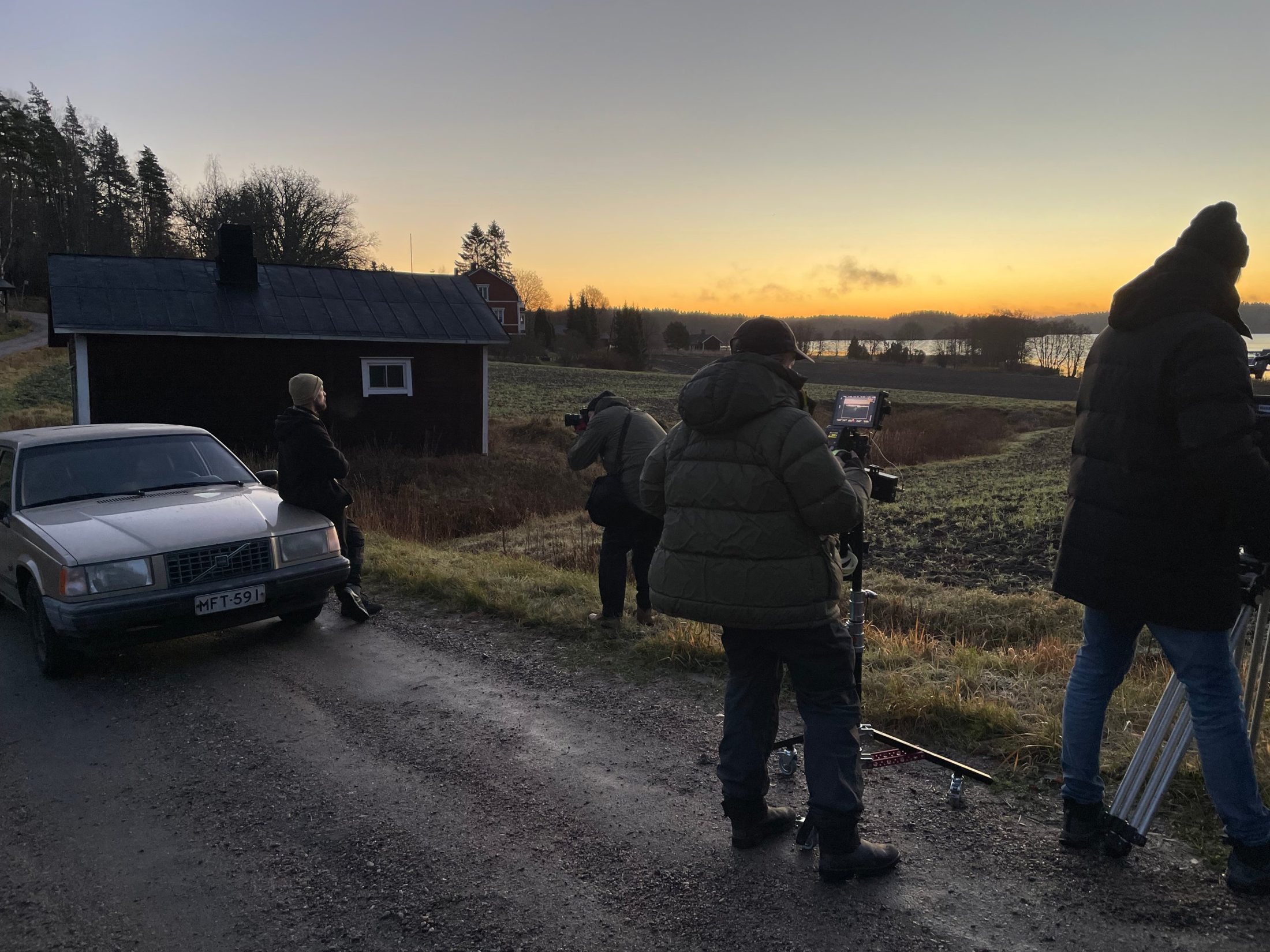 Crew at sunset by a red cabin in the Finnish countryside.