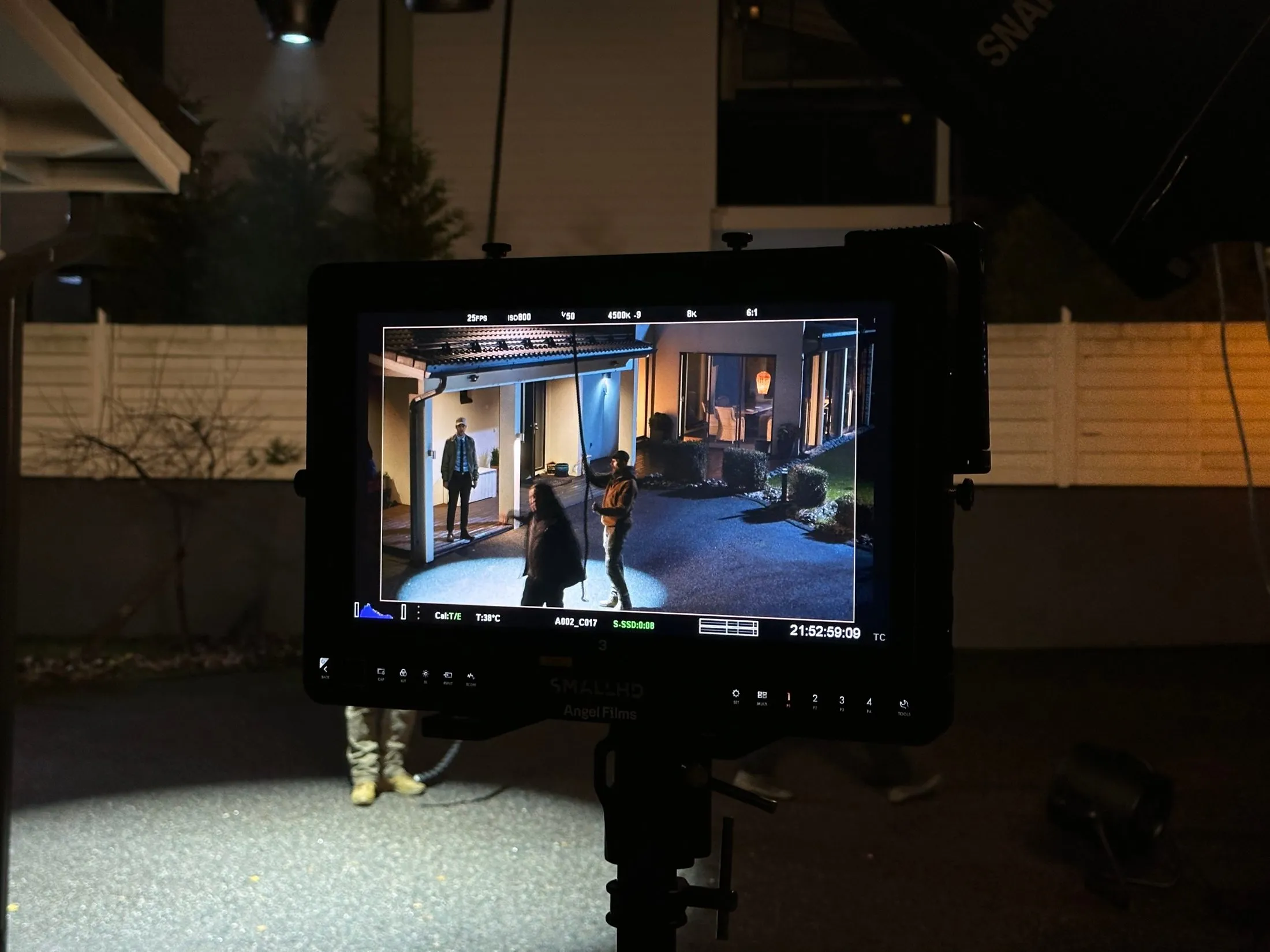 A monitor displays a night scene outside a house.