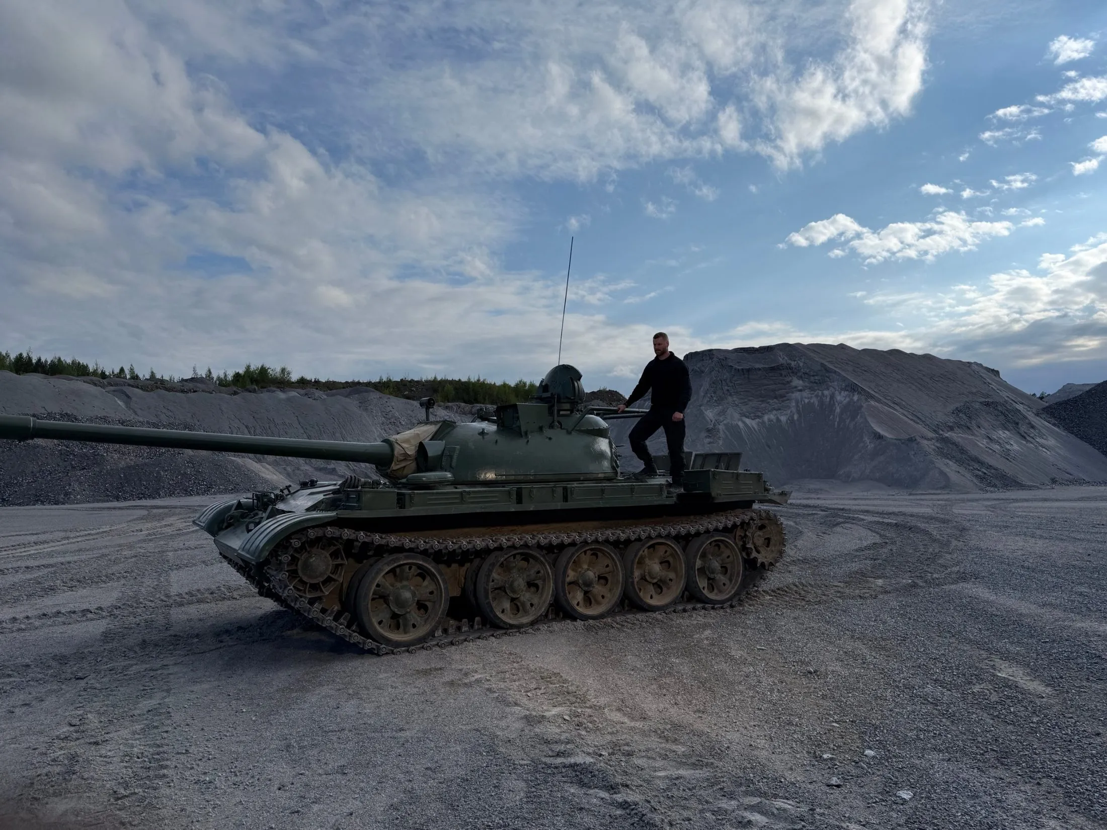 A person standing on a tank in a gravel quarry.