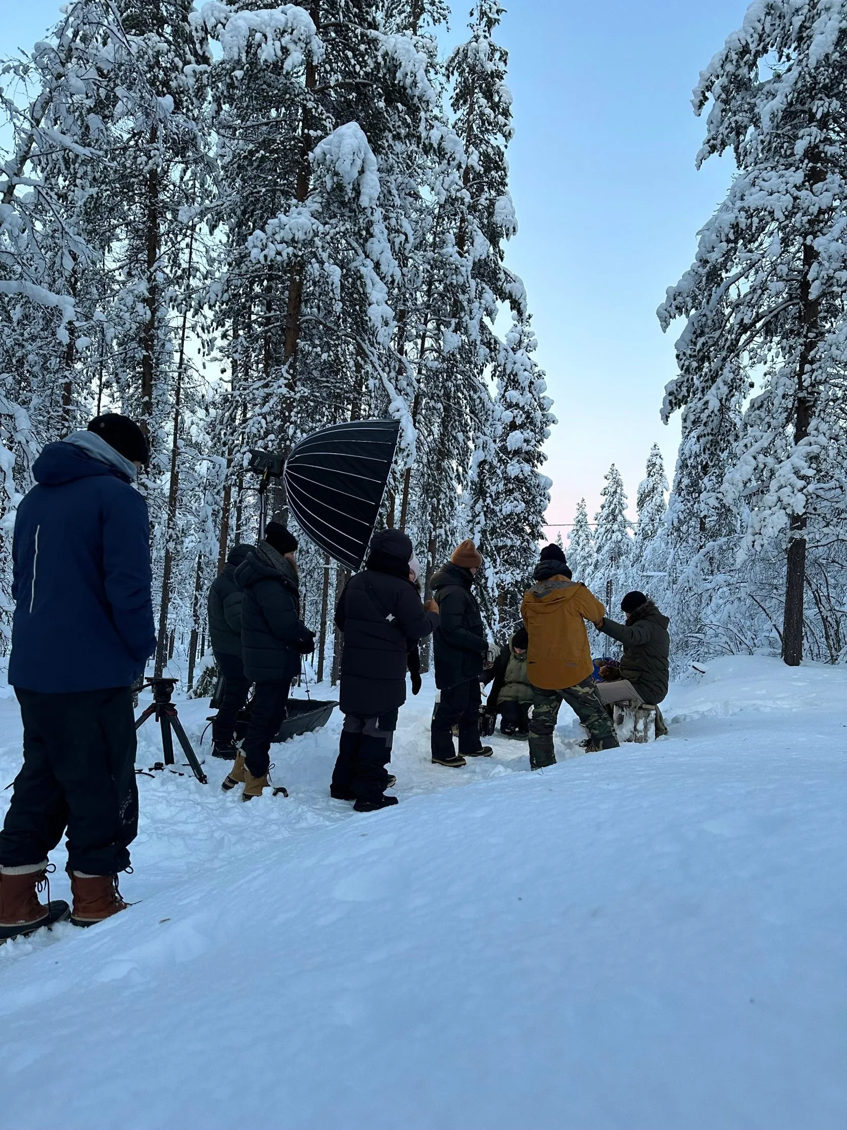 Film crew and a softbox in a snow-covered forest.