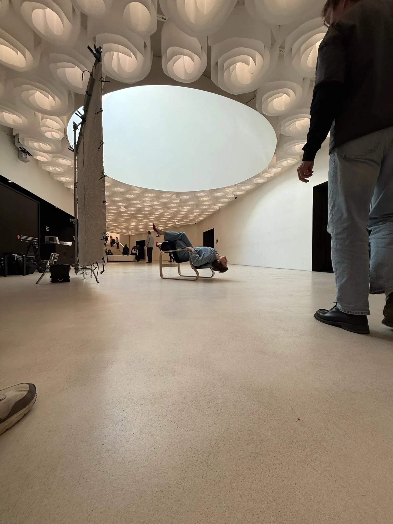 Film crew and lighting equipment in a white exhibition space at Amos Rex.
