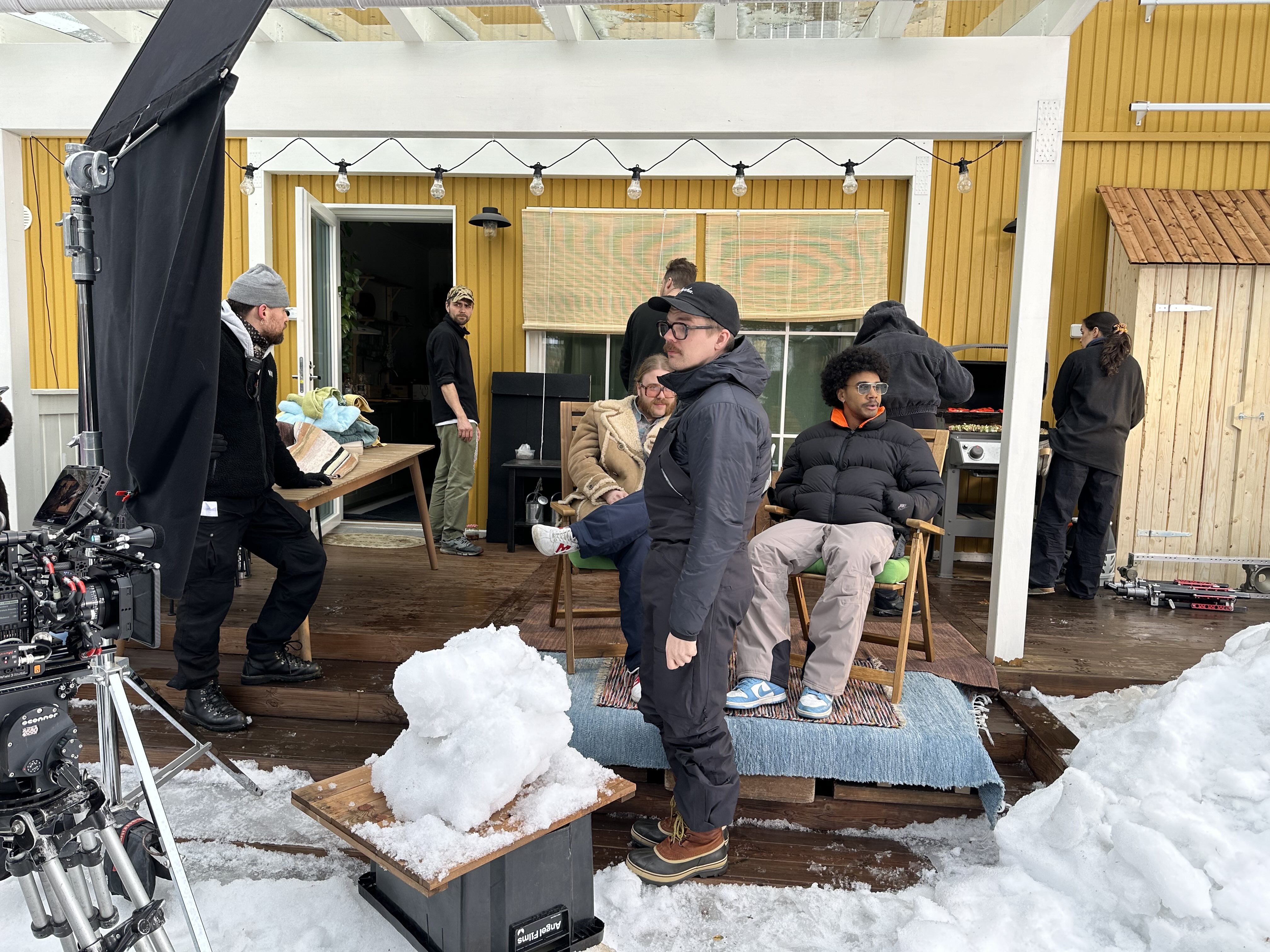Kuvausryhmä talon terassilla lumisen rekvisiitan äärellä S-marketin kuvauksissa.