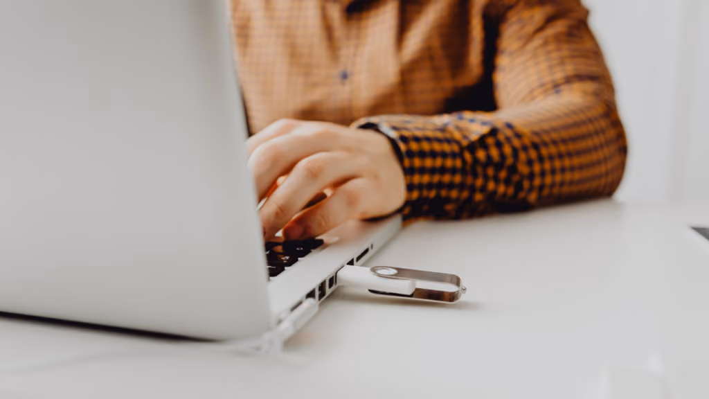 Personne travaillant sur un ordinateur portable à côté d’une clé USB