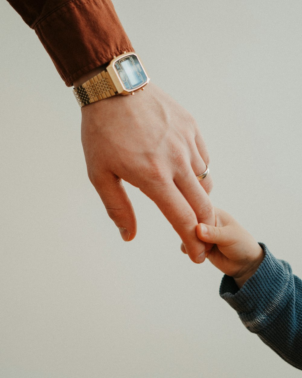 An adult hand holding a small child’s hand