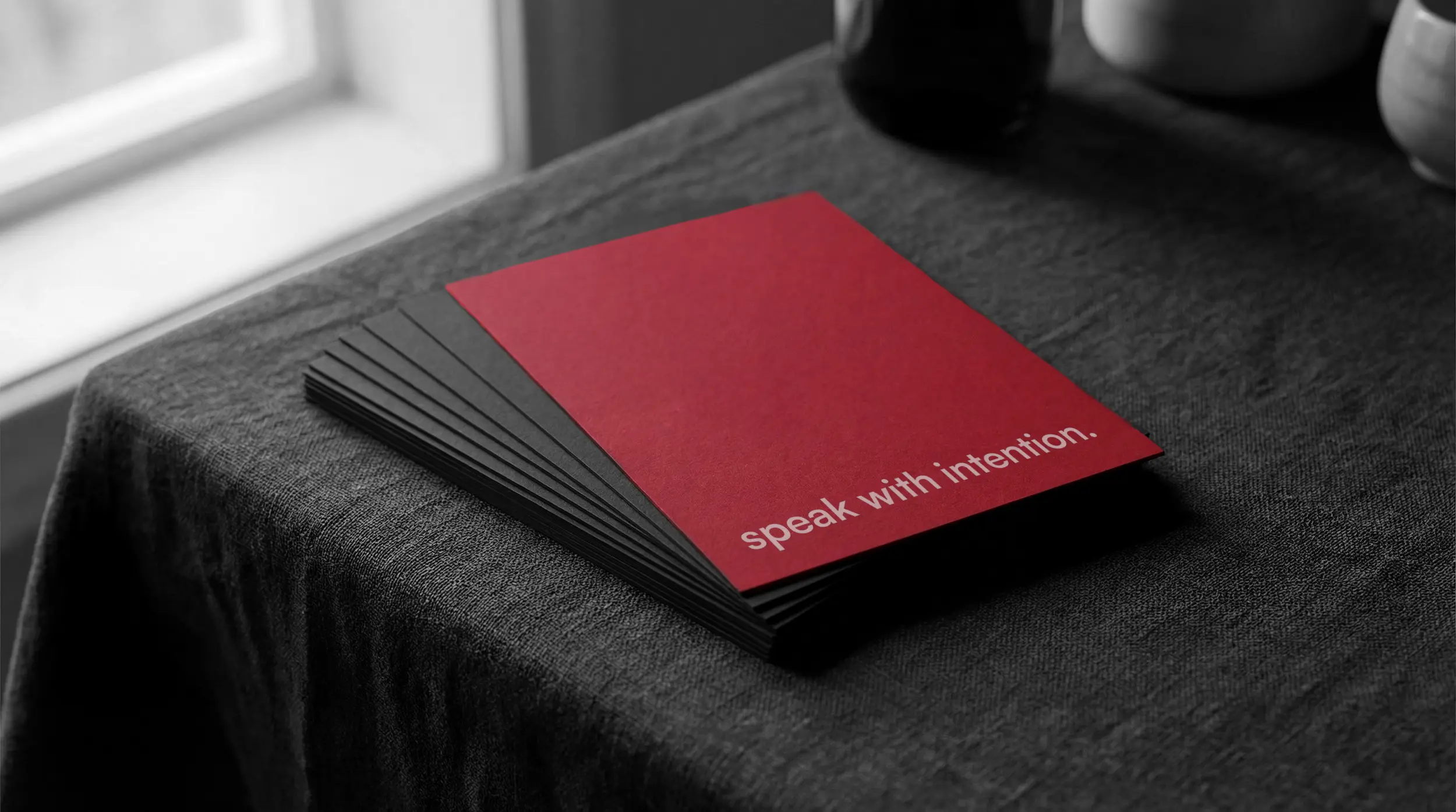 Stack of black cards with a red card on top that reads 'speak with intention.'
