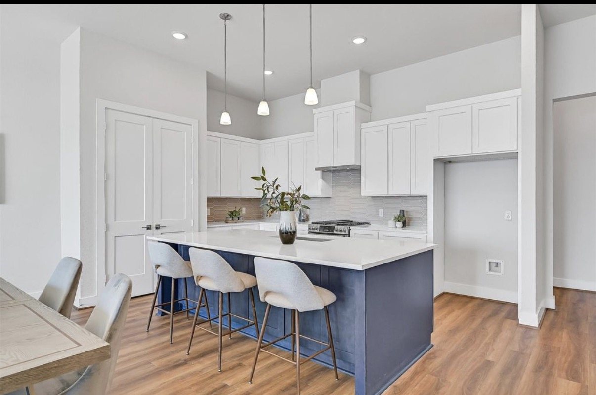 Kitchen with a navy island, counter stools and white cabinetry