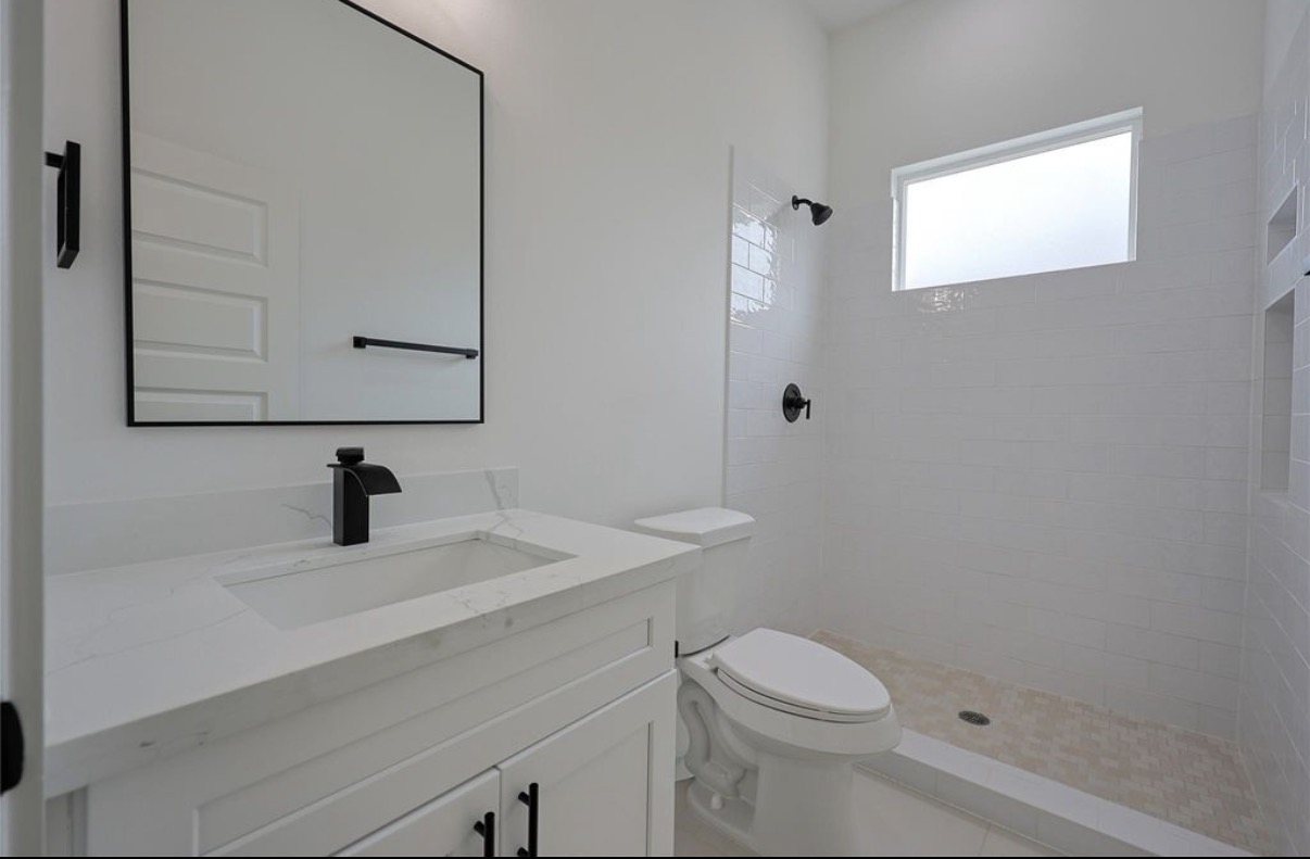 Bathroom with a white vanity, black fixtures and a walk-in shower