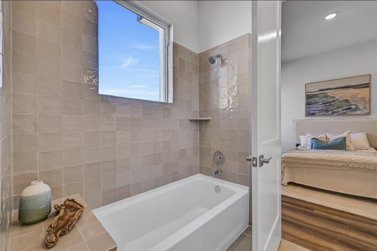 Bathroom with a tiled tub surround and a window above the tub