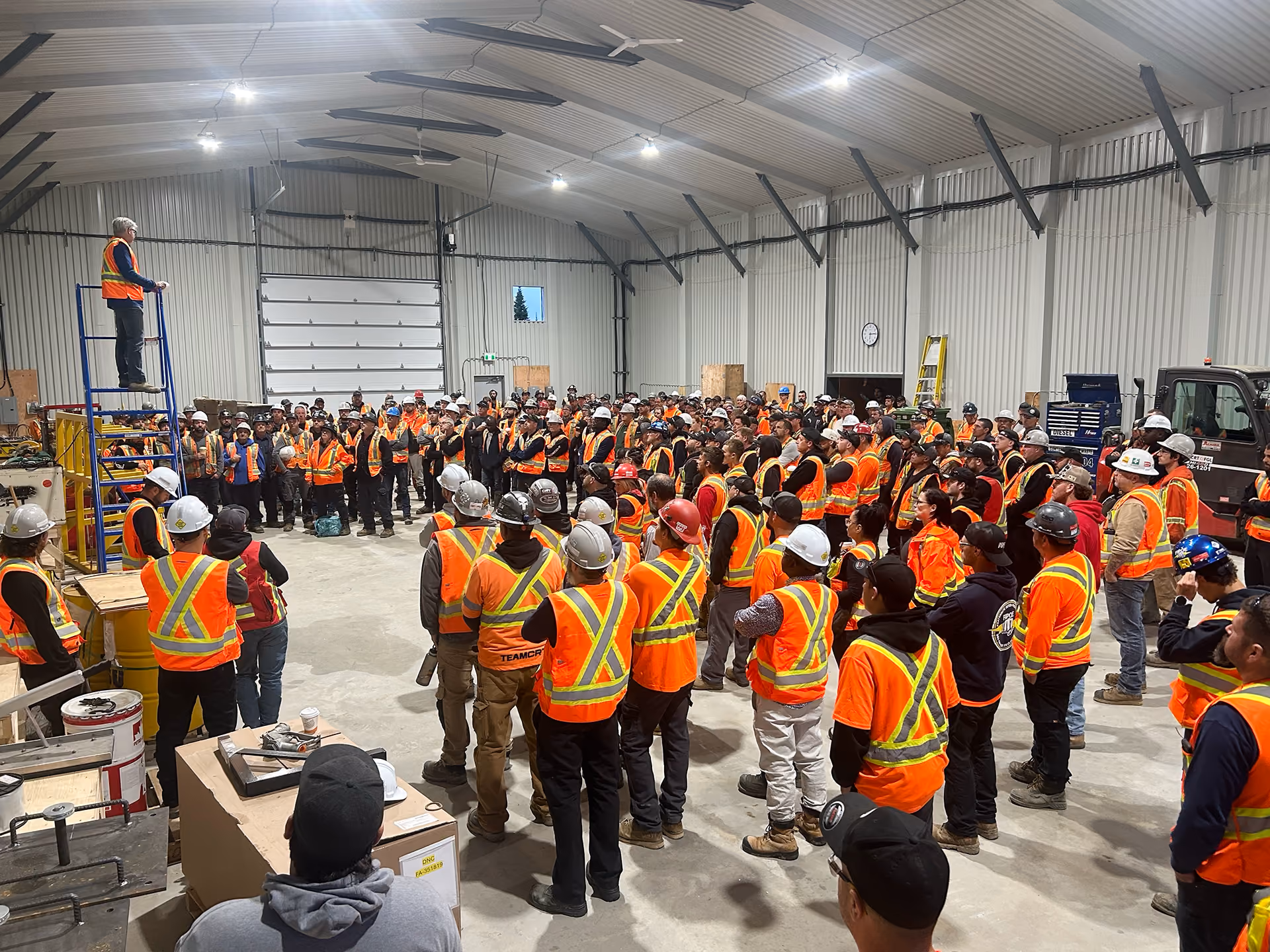 Employés du Groupe Gilbert réunis lors d’un rassemblement d’équipe dans un atelier industriel.