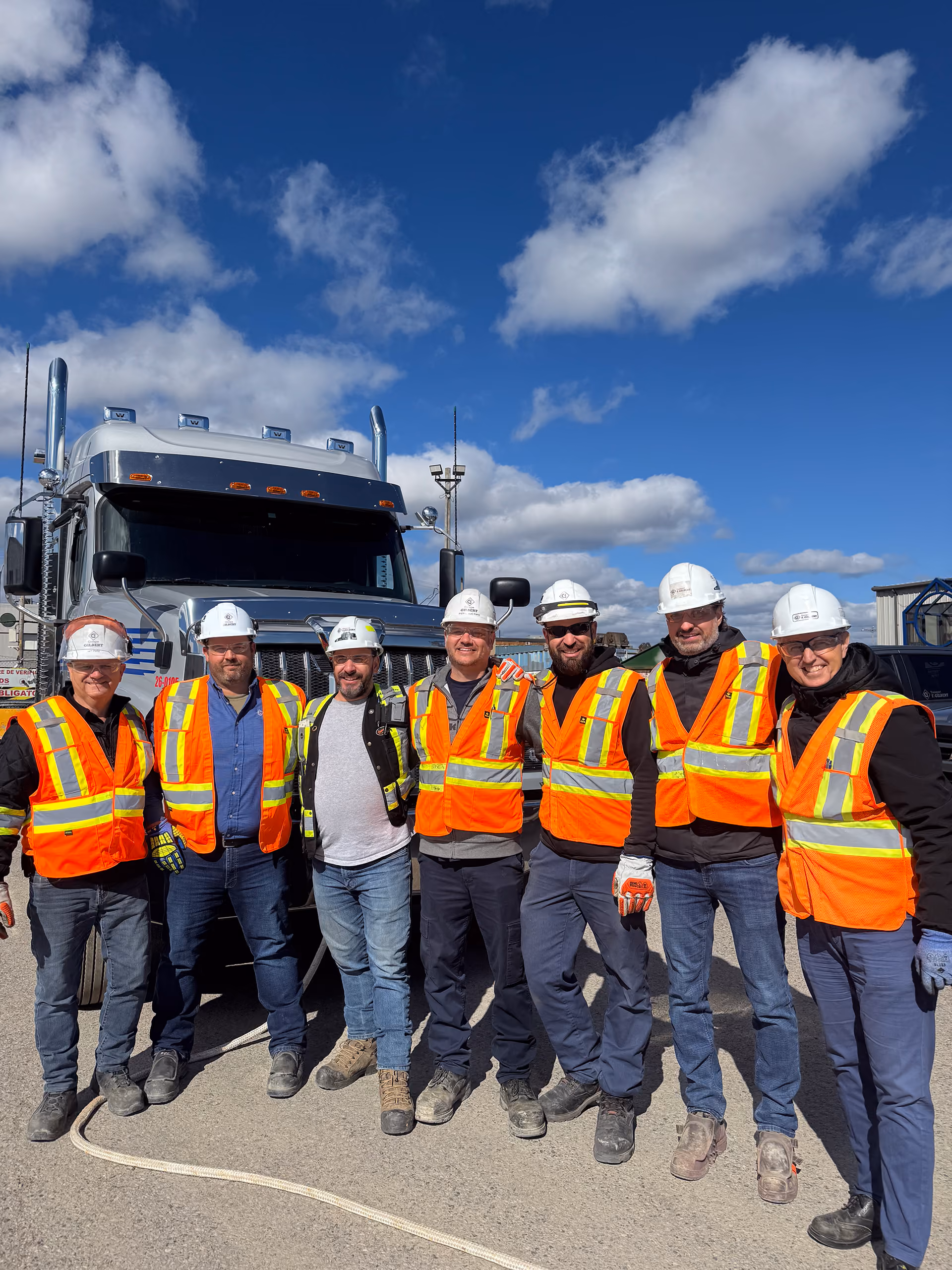 Employés du Groupe Gilbert en équipement de sécurité réunis devant un camion de chantier.